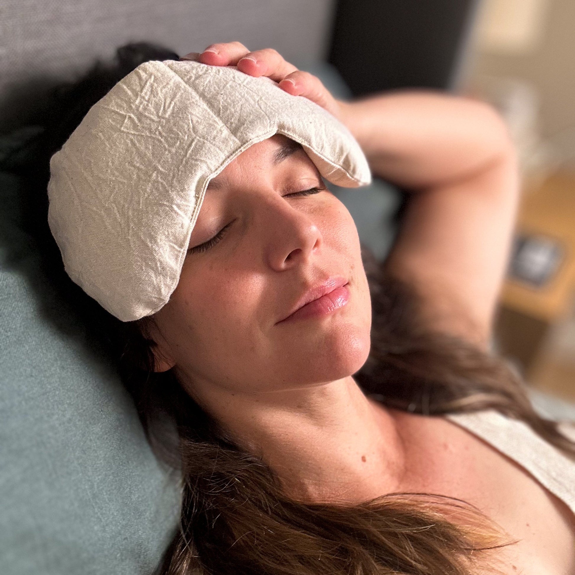 Woman relaxing with meditation pillow on forehead for natural pain relief