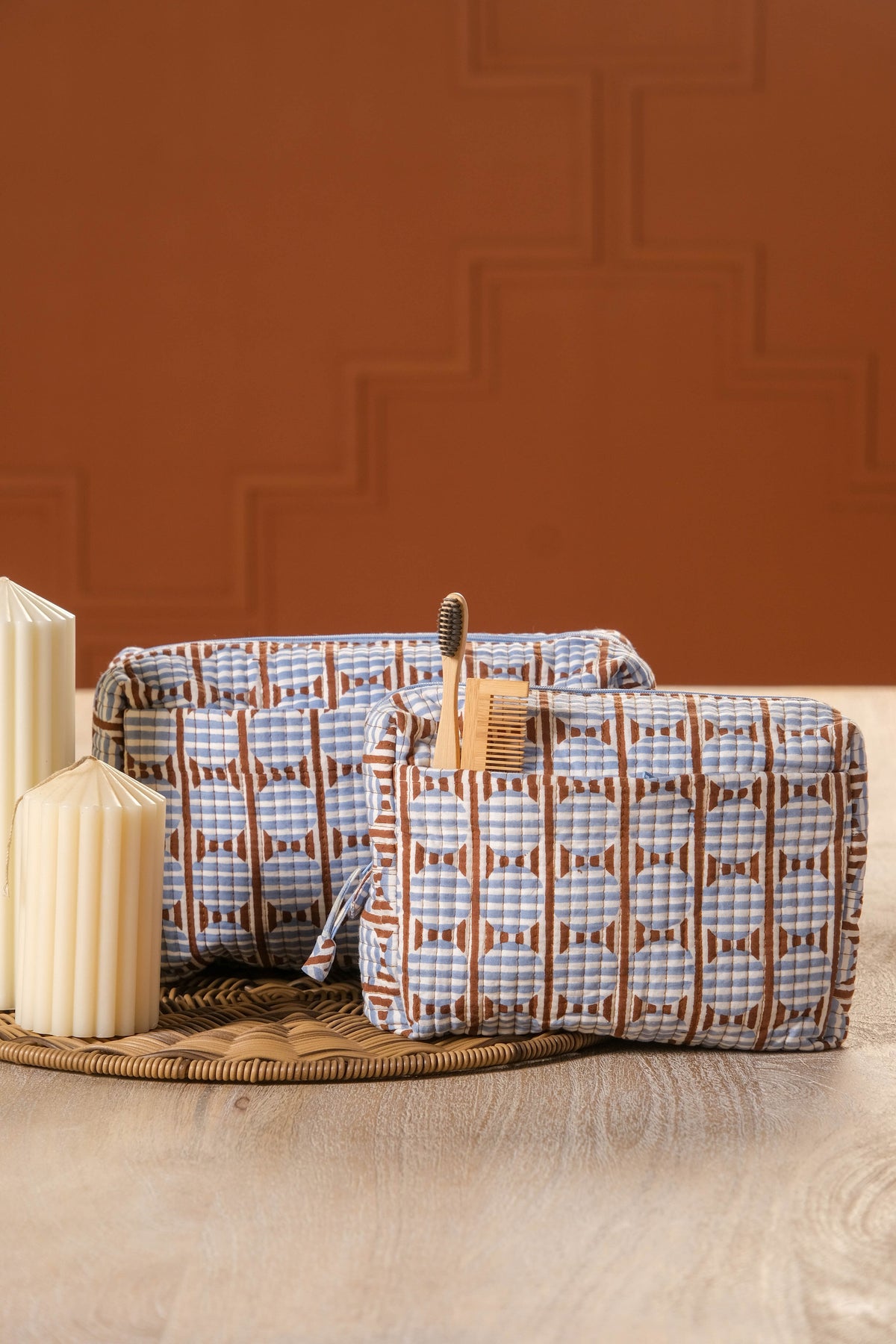 Brown and blue striped circle blockprint travel pouches on woven mat with candles