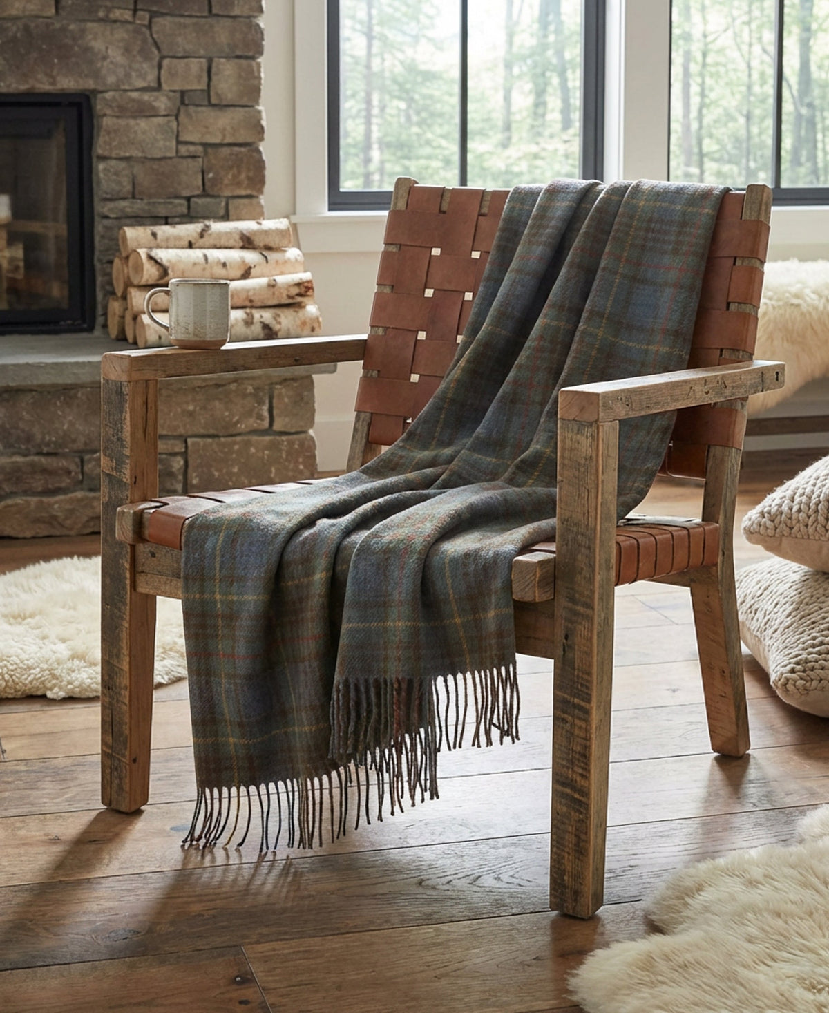 Antique Hunting Stewart tartan wool throw with fringe draped over a rustic leather and wood chair by a stone fireplace.