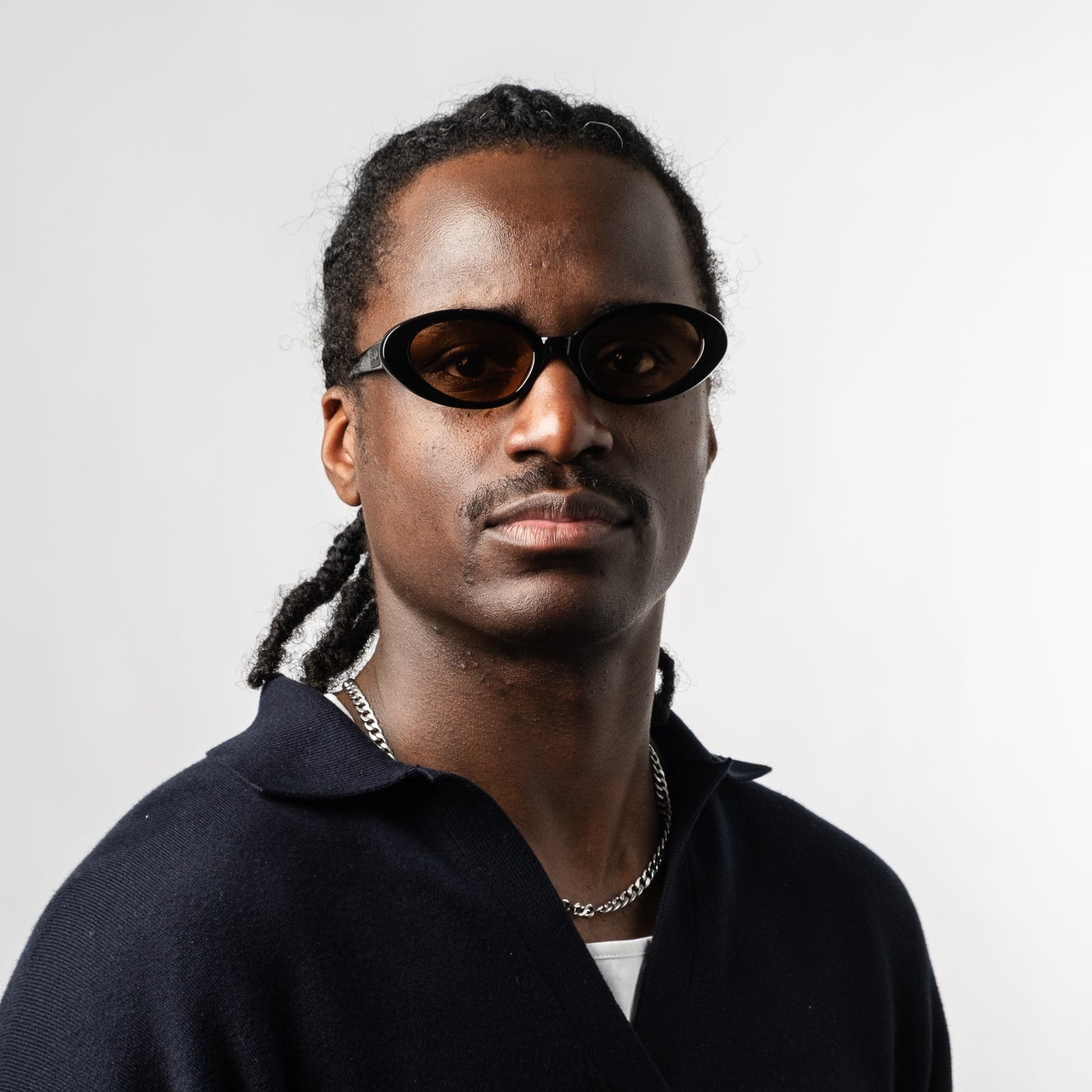Male wearing Sad Eyewear Bloom oval sunglasses in black with tinted bronze lenses