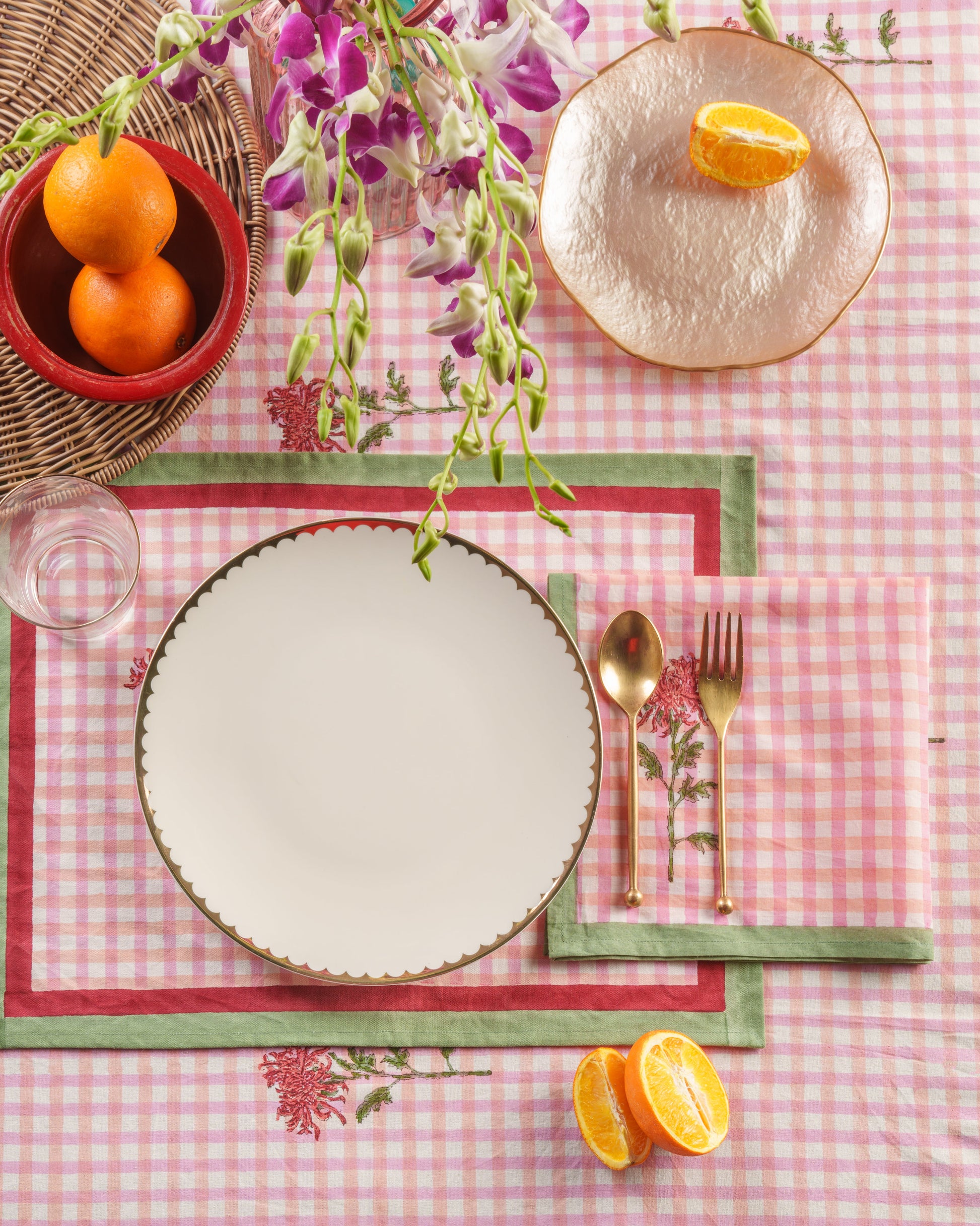 Pink gingham napkin table setting with goldware and oranges by Inner Child