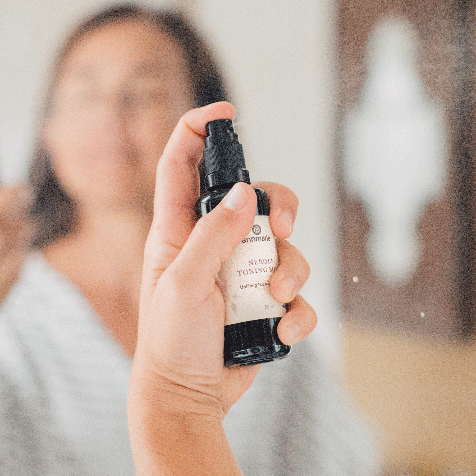 Person spraying Annmarie Neroli Toning Mist onto the face to refresh and hydrate skin.
