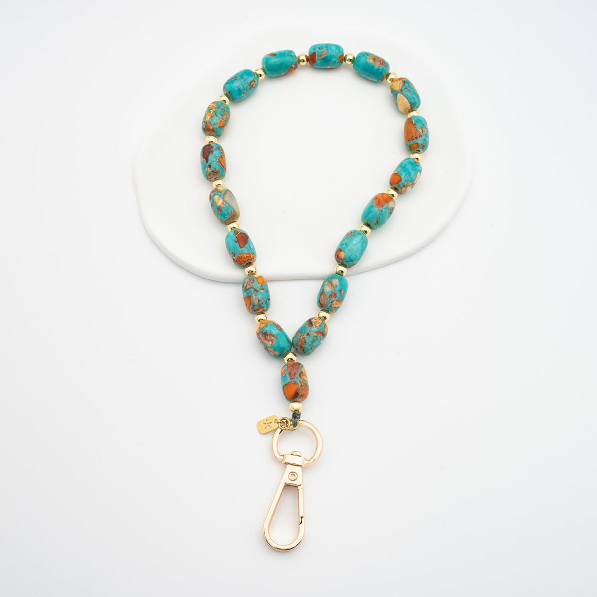 Sierra Bloom turquoise and orange beaded wrist strap with gold swivel clasp on white