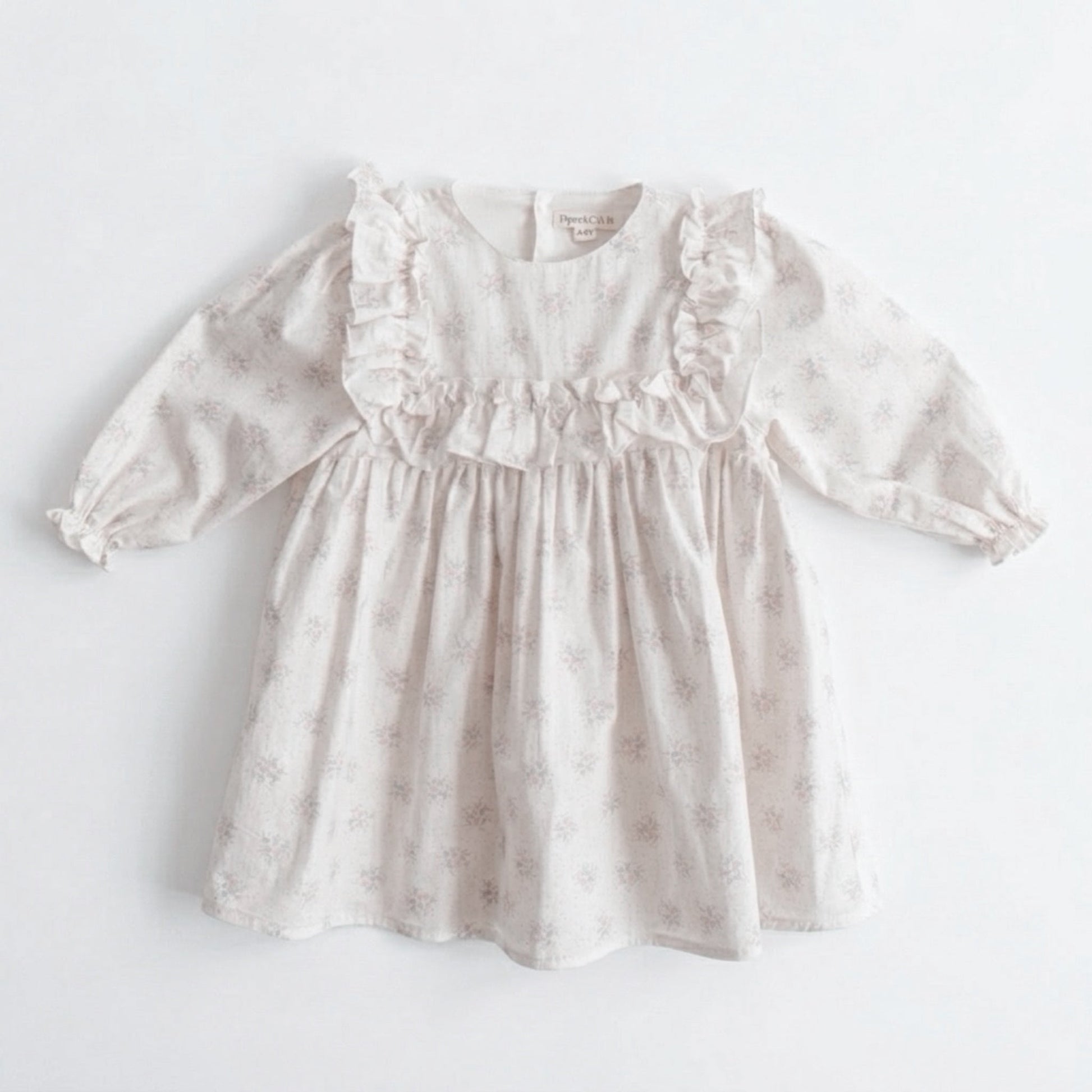 White baby dress with ruffled details on a light gray background