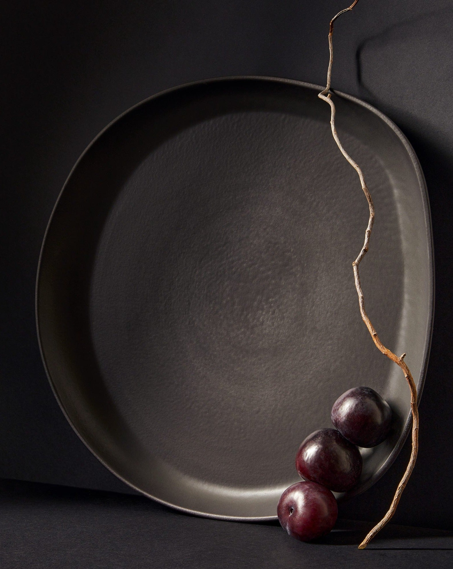 A stoneware serving platter with organic forms and a matte finish, presented on a table with food items arranged on top.