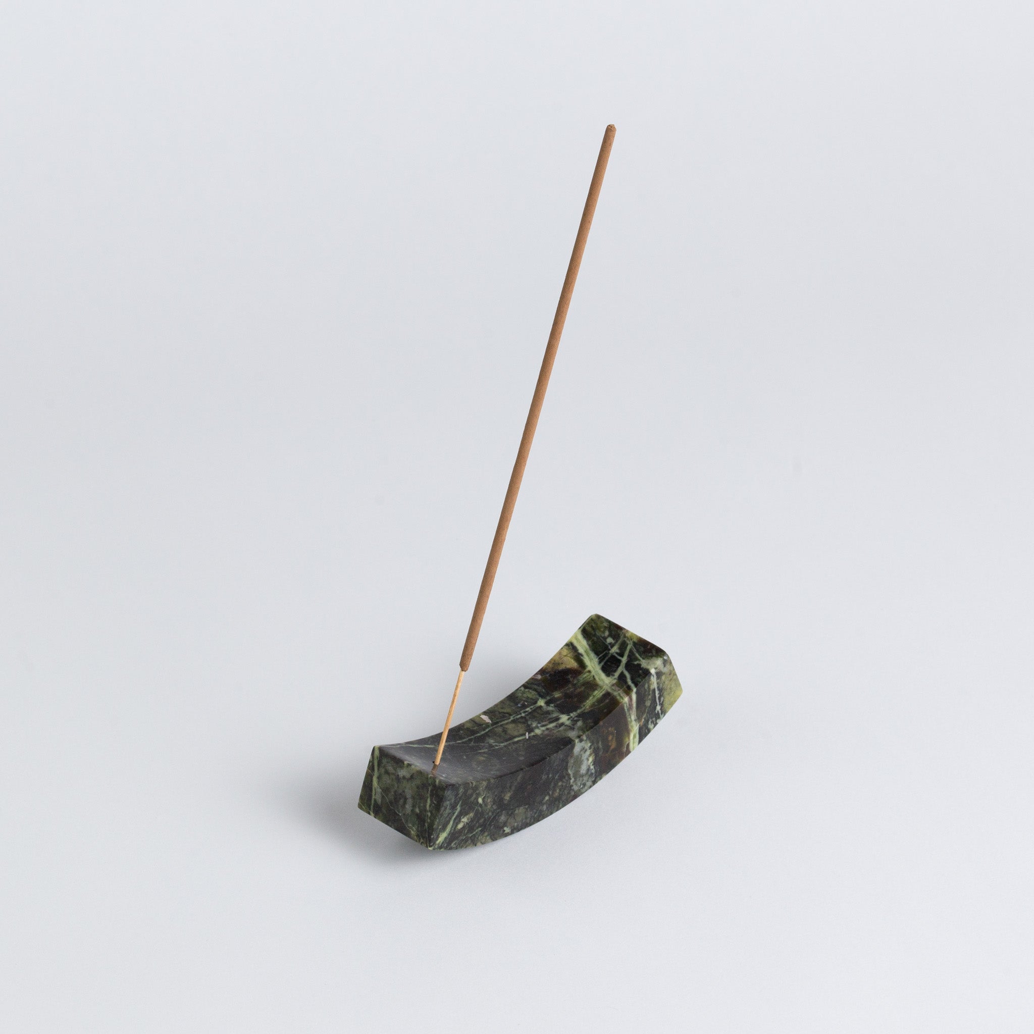 Smooth, handcrafted serpentine stone curved incense holder on a white background.