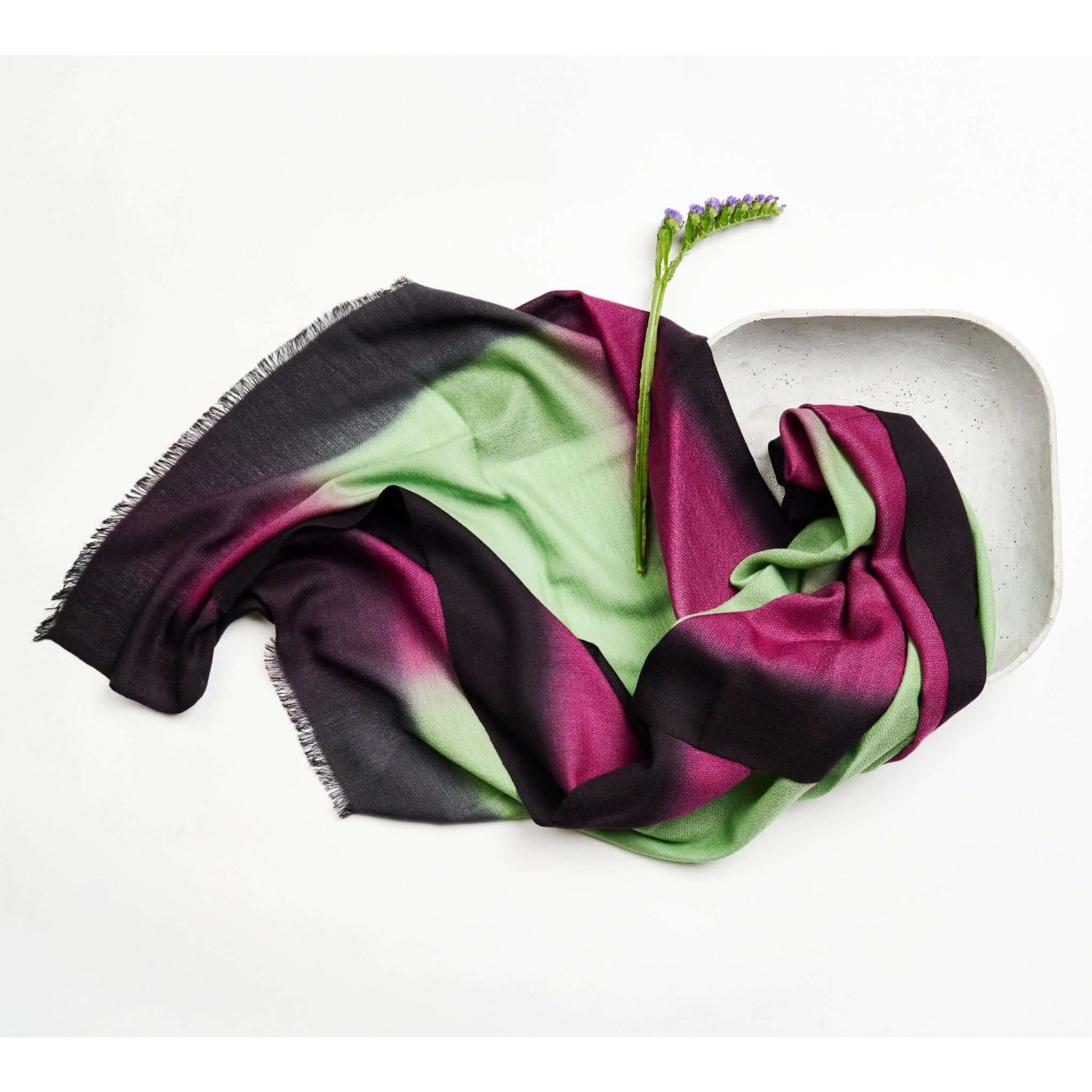 Iris Courtyard Green Purple Hand Woven Cashmere Merino Scarf displayed artistically with a flower in a bowl.