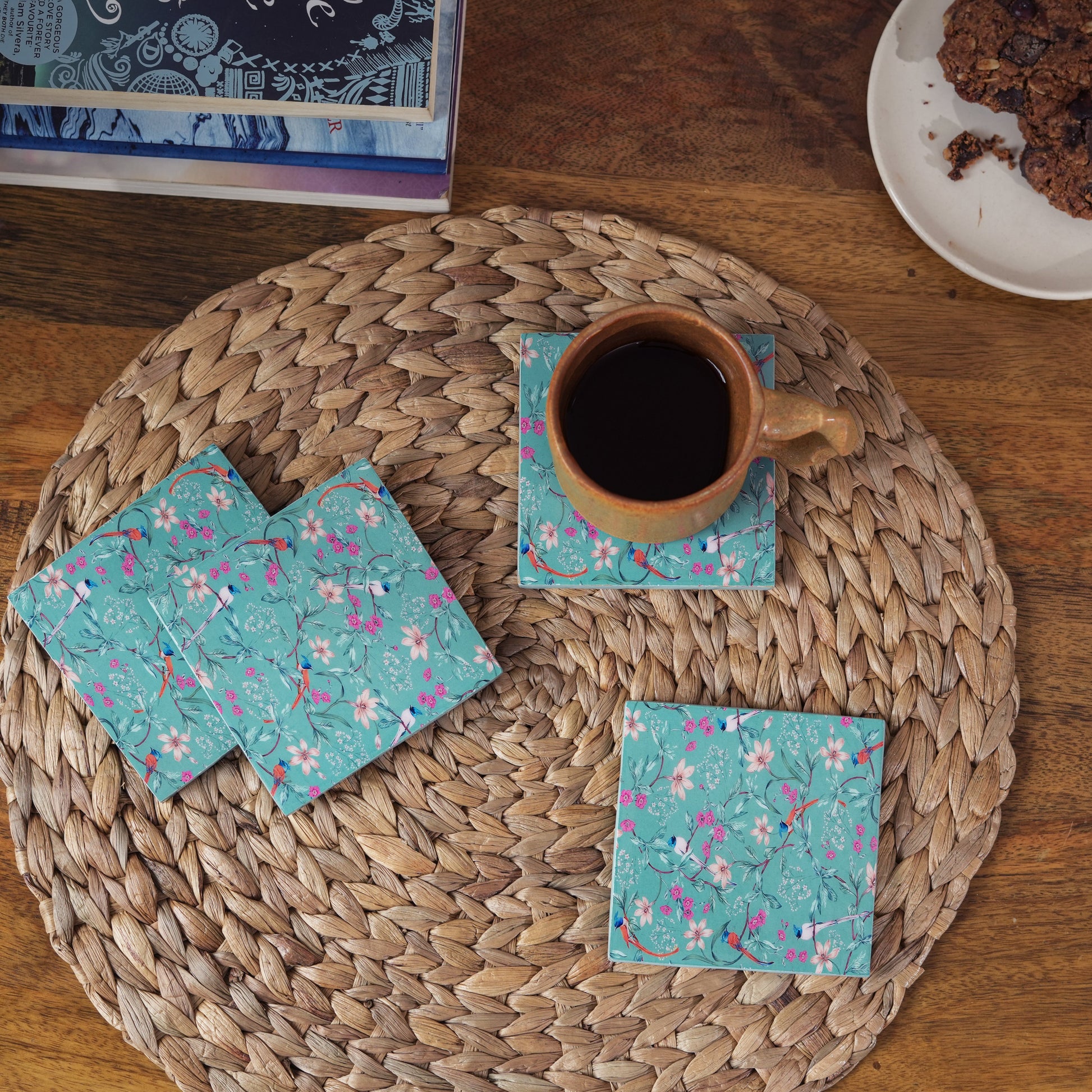 Teal floral coasters with a cup of coffee on a woven placemat
