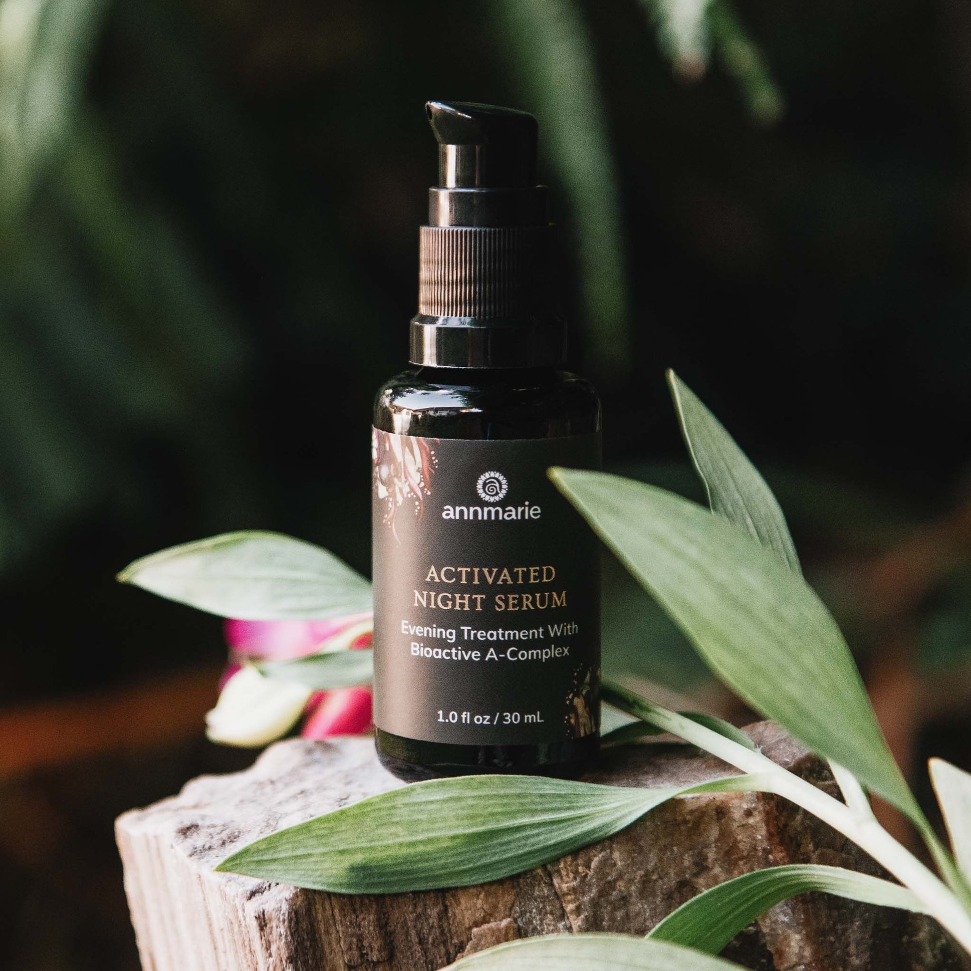 Activated Night Serum evening treatment with Bioactive A-Complex displayed on a natural wood surface surrounded by green leaves.