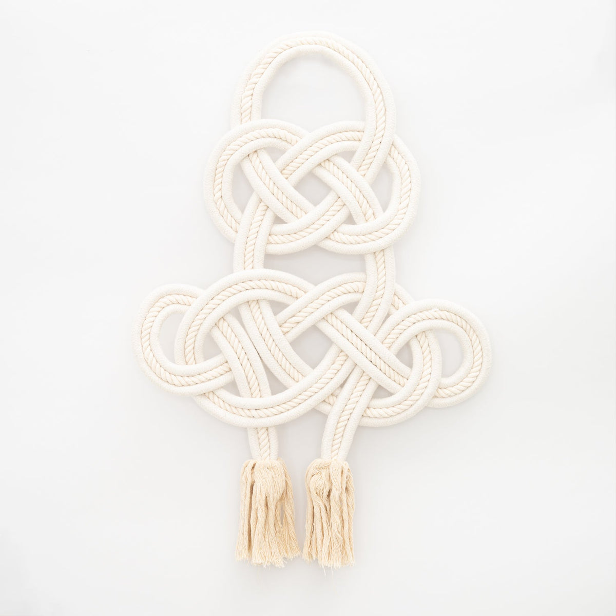 Coexist knotted cream cotton rope wall hanging with tassels on white