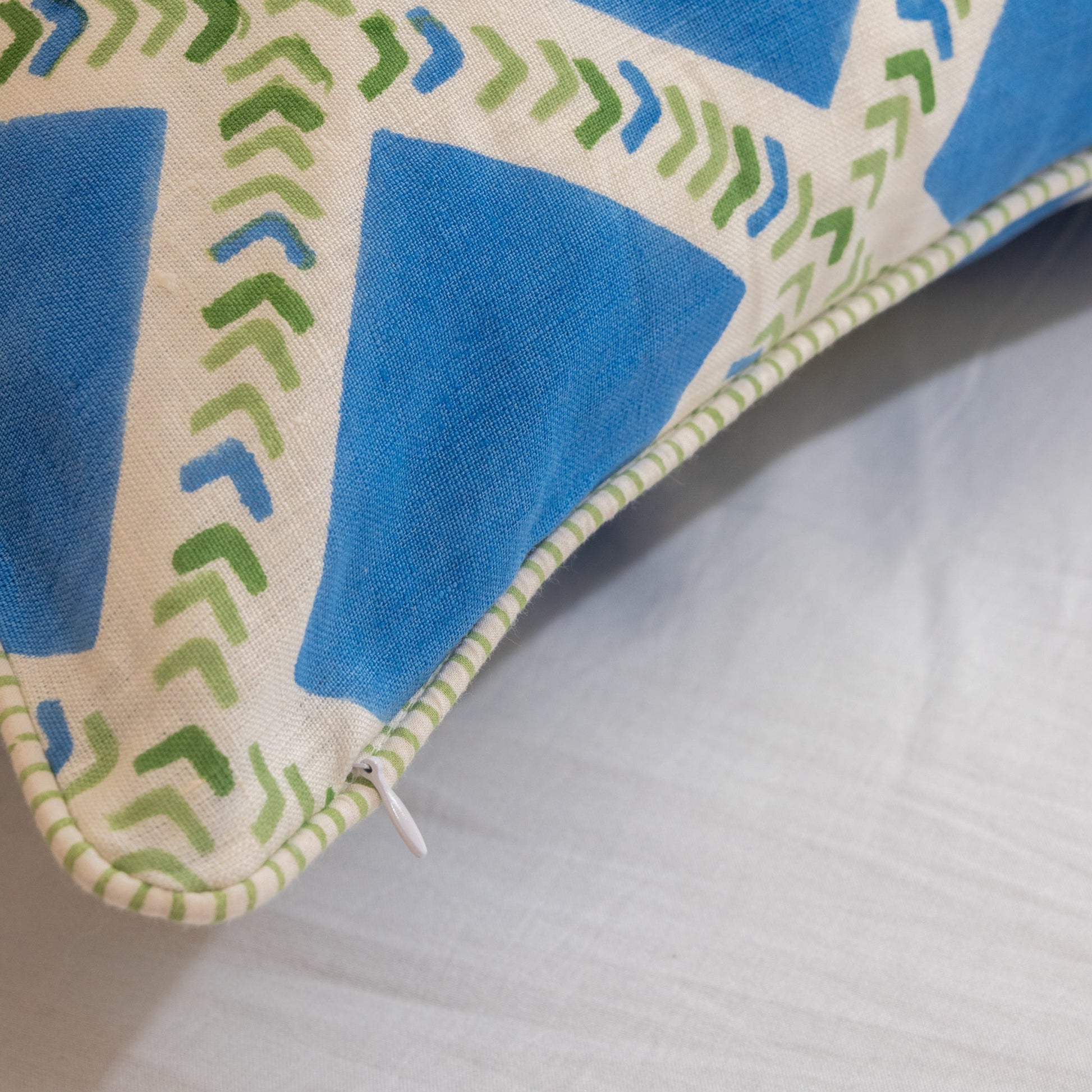 Close-up of a Hand block printed linen pillow cover with interlocking geometric green and blue chevron  print in natural dyes placed on a white background