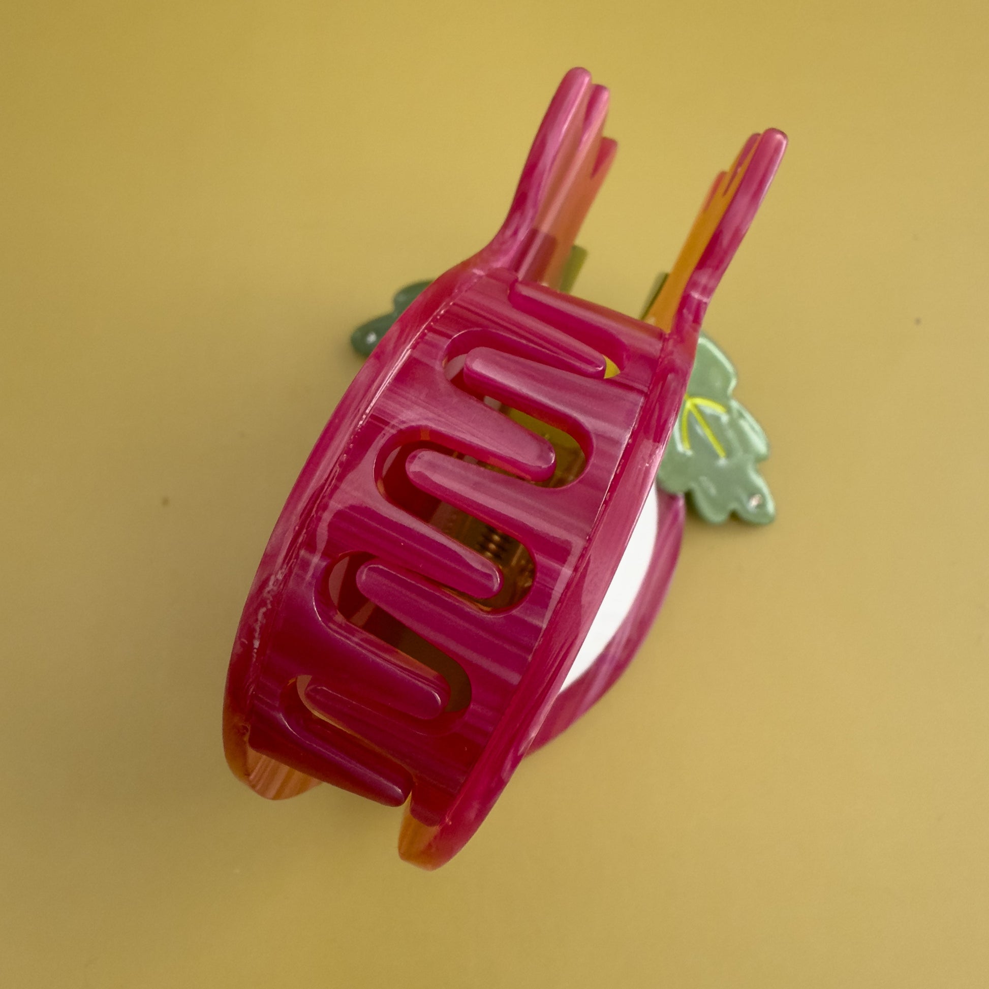 Decorative pomegranate hair claw with a green leaf. Don't let this tough exterior fool you! Beneath its rosy glow lies a treasure chest of tiny, ruby-red jewels, each one a delightful explosion of sweet-tart goodness.

Pomegranate hair claw season is here and we can help but wearing it too!