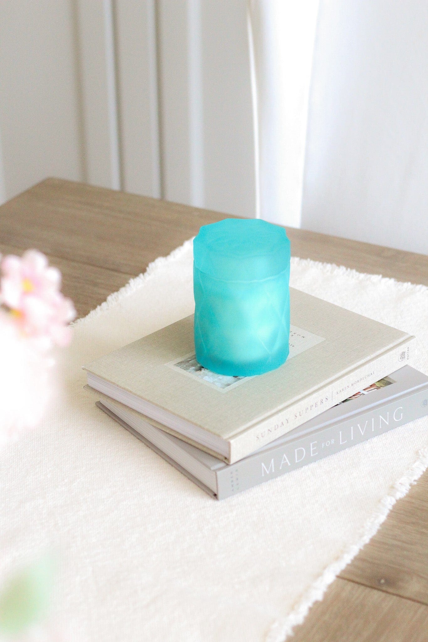 light teal color glass candle jar on home decor coffee table books on kitchen table