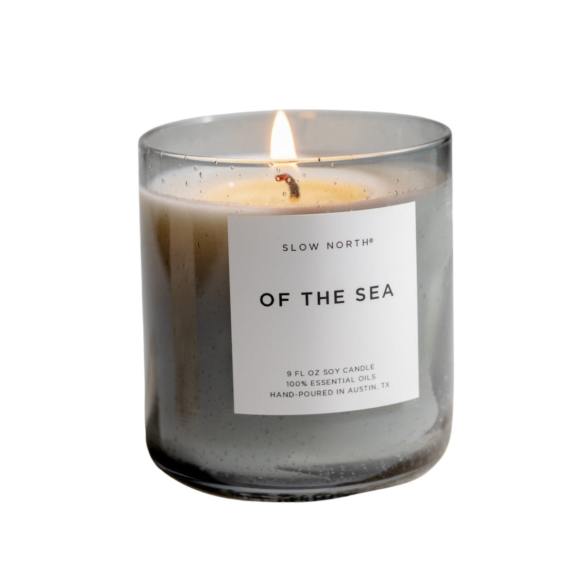 Candle labeled 'Of the Sea' by Slow Nordik on a stone surface with a neutral background