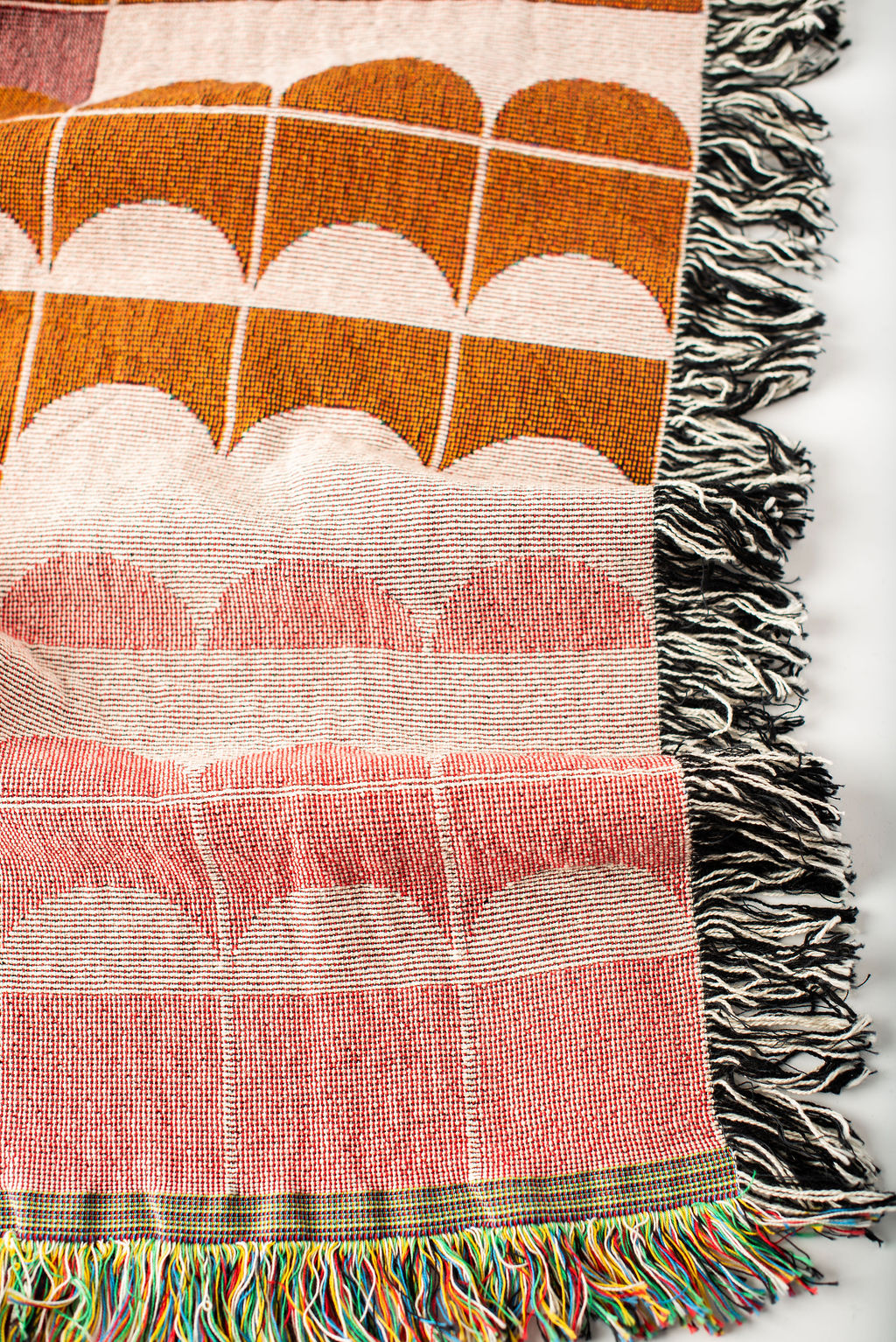 Close-up of Quinn Blush pink, cream, and ochre geometric woven cotton throw with fringe
