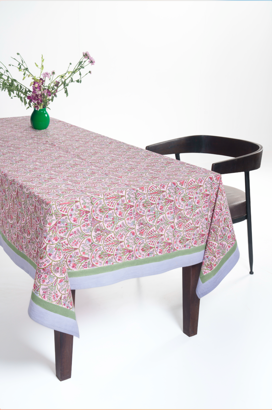 Pink arch blockprint tablecloth on rectangular table with green vase and dark chair