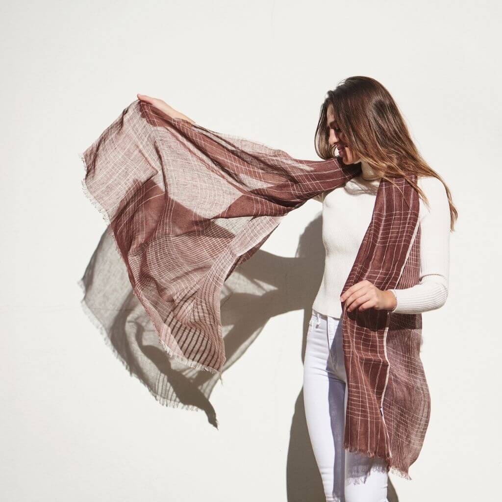 Auro Cinnabar Handwoven Earthy Rust Maroon Linen Scarf being elegantly worn by a woman against a plain background.