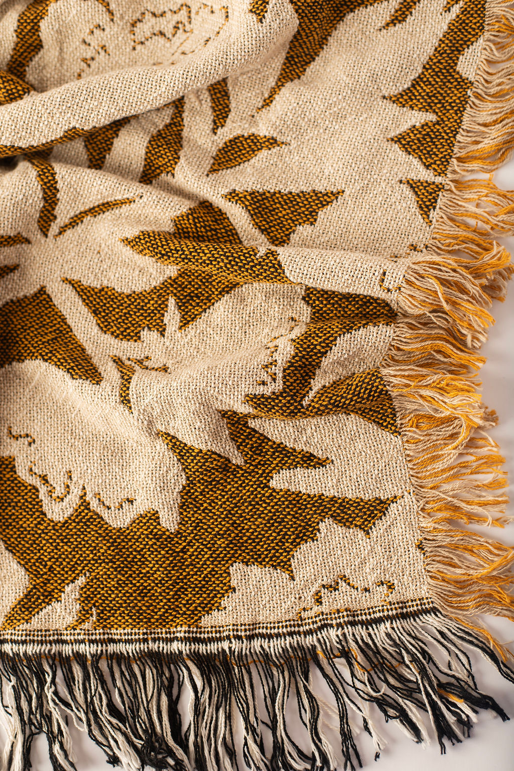Close-up of Addy Ochre gold and cream floral woven cotton throw with fringe