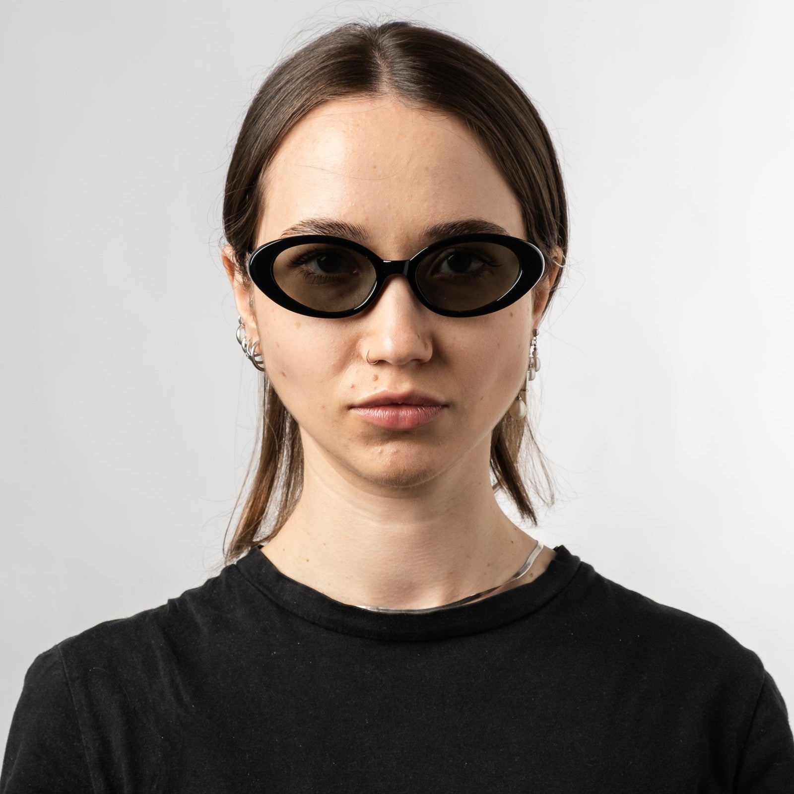 Female wearing Sad Eyewear Bloom oval sunglasses in black with tinted olive lenses