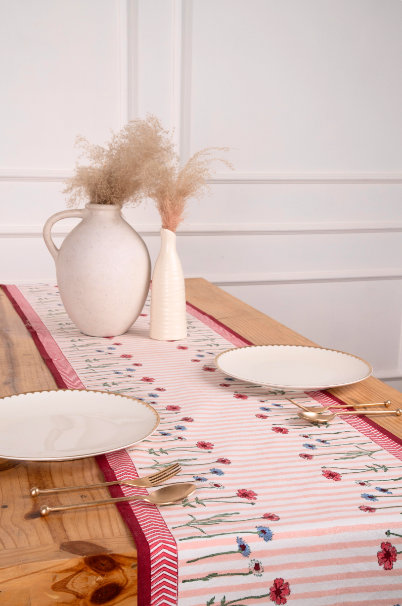 Pink striped wildflower tablerunner with red/blue flowers on wooden table, white plates