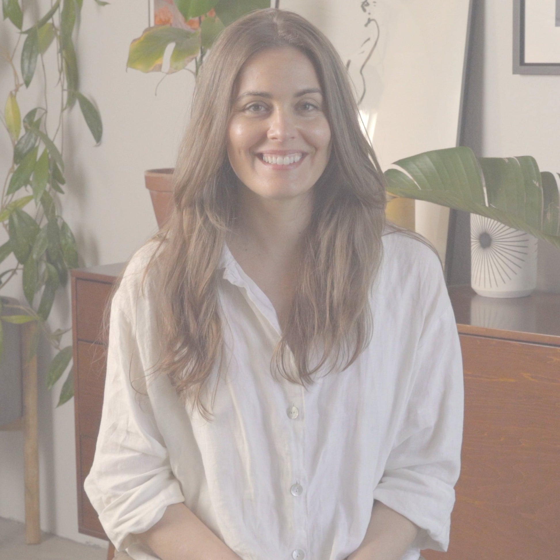 Video of woman sitting indoors surrounded by plants, explaining concentrated boosting elixirs