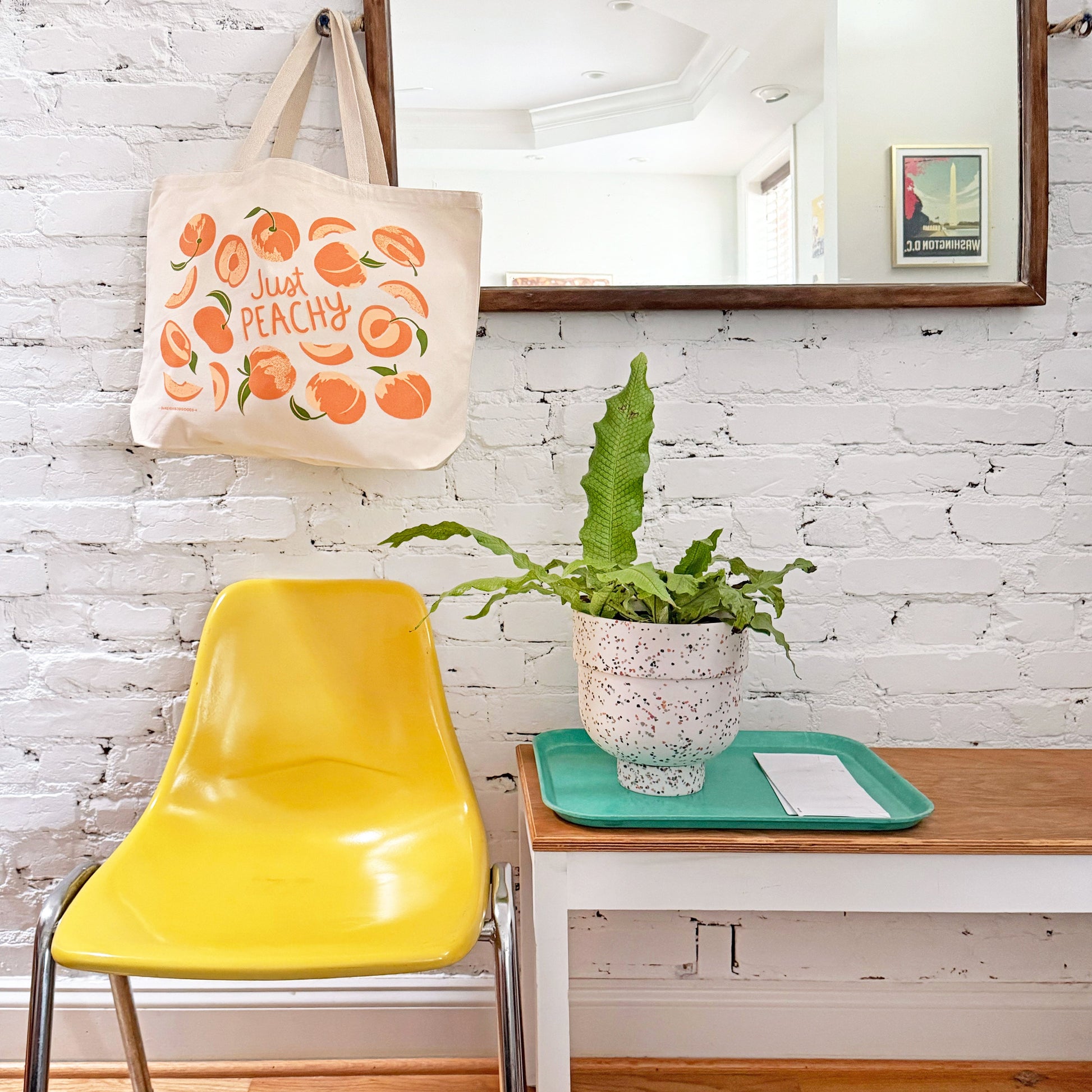 Peach tote bag hangs on a mirror hook.
