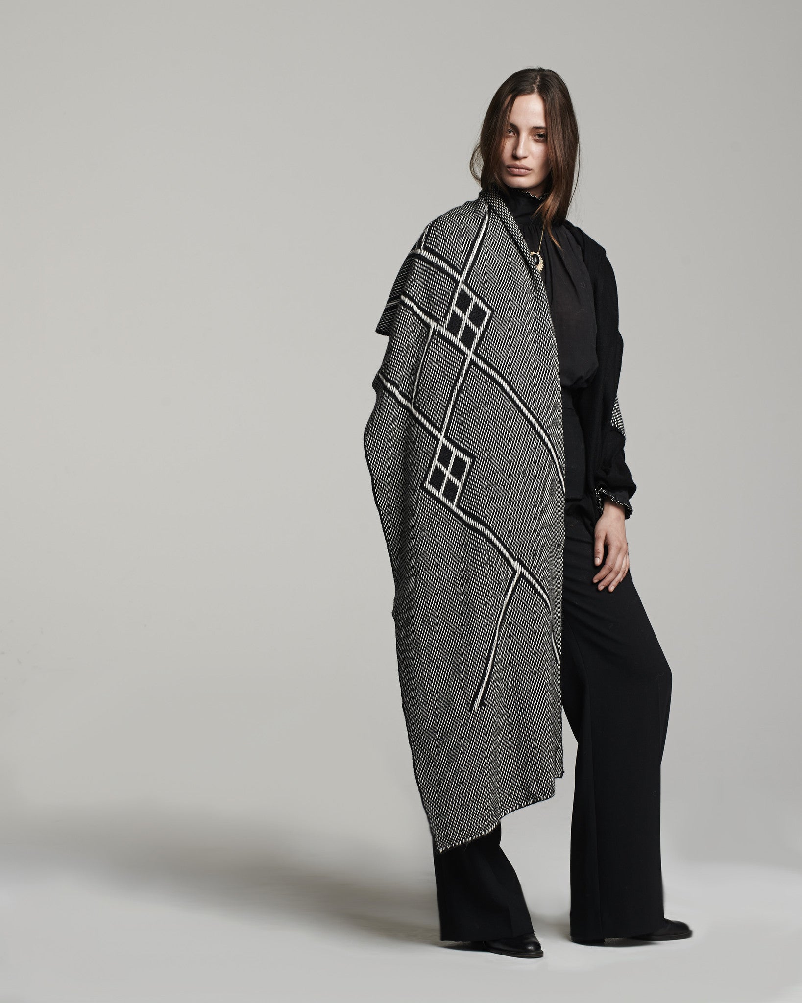 Model wearing a black and ivory shawl with geometric patterns