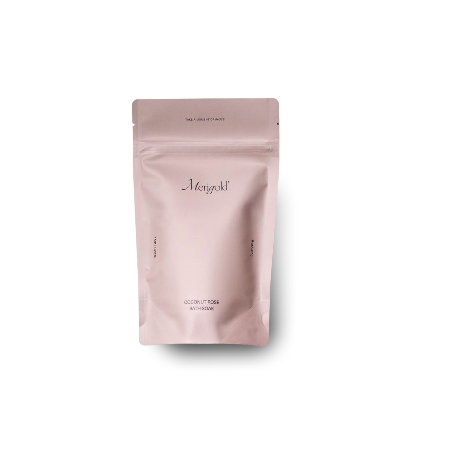 Merigold Coconut Rose Bath Soak is in a dusty rose colored resealable bag, featuring minimalist design and ingredients like organic coconut milk and dried rose petals. Photographed on a white background. 
