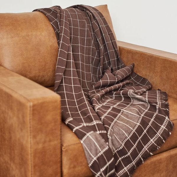 Treacle Checks Pattern Organic Cotton Handloom Throw draped over a brown armchair, showcasing its elegant design.
