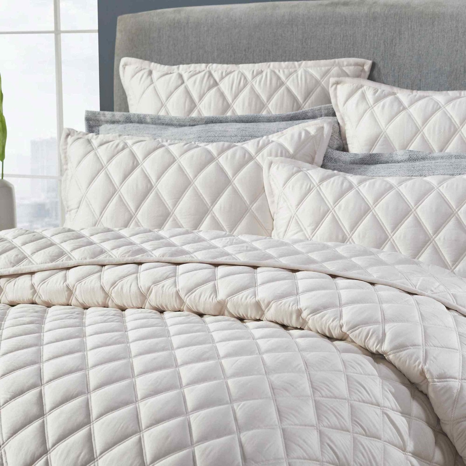 CL-180-9496_3|Close-up of cream diamond-quilted coverlet and pillows, highlighting soft texture and intricate stitching detail.