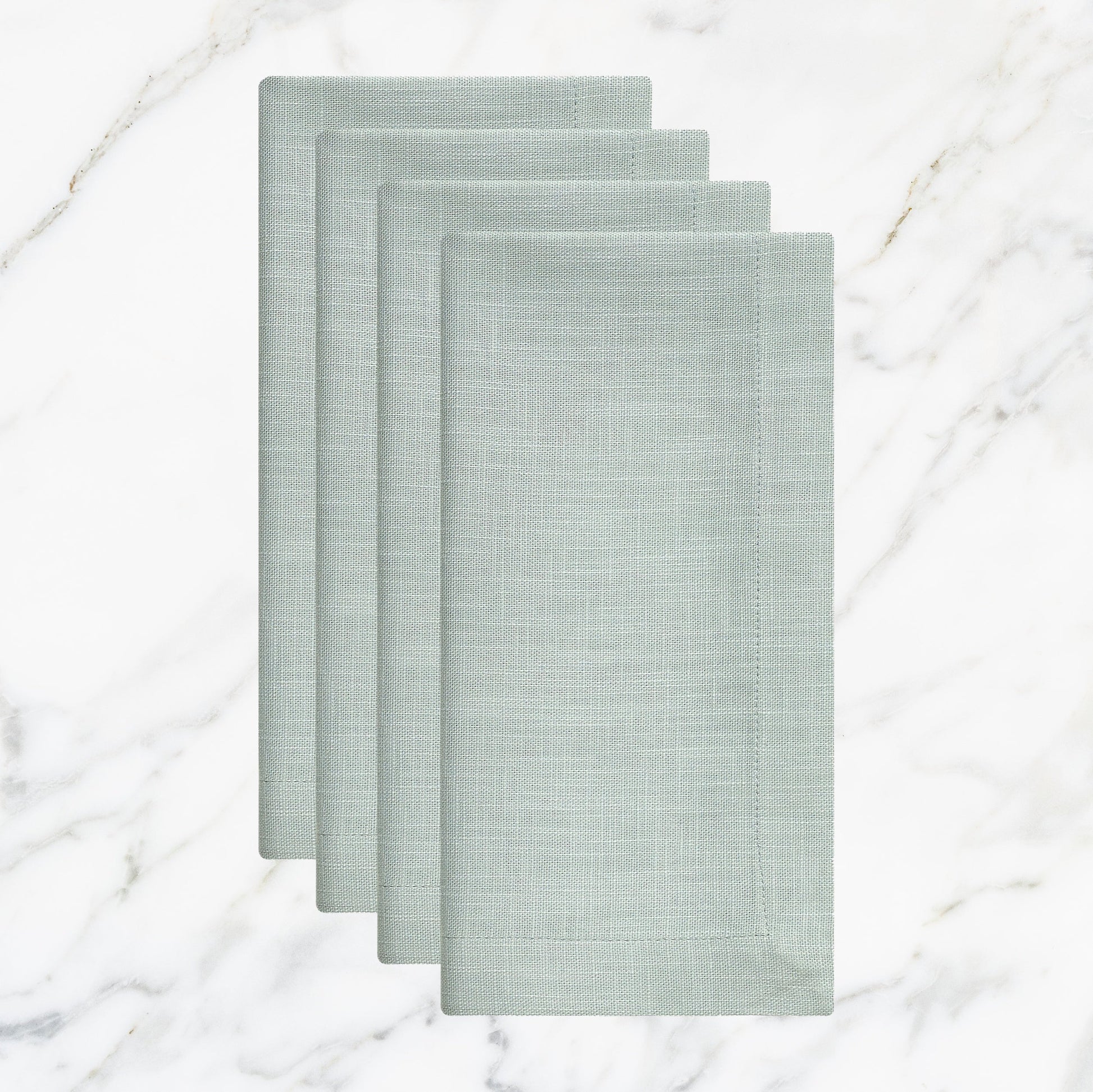 NP-4806-2020_1|Four folded light blue linen-look napkins, elegant table setting accessories on a white marble background. Durable fabric.