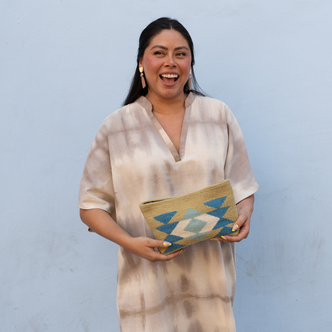 Woman carrying handwoven pouch with abstract Zapotec butterfly design in bright spring colors, featuring internal pocket; perfect for makeup, wallet, or daily essentials.