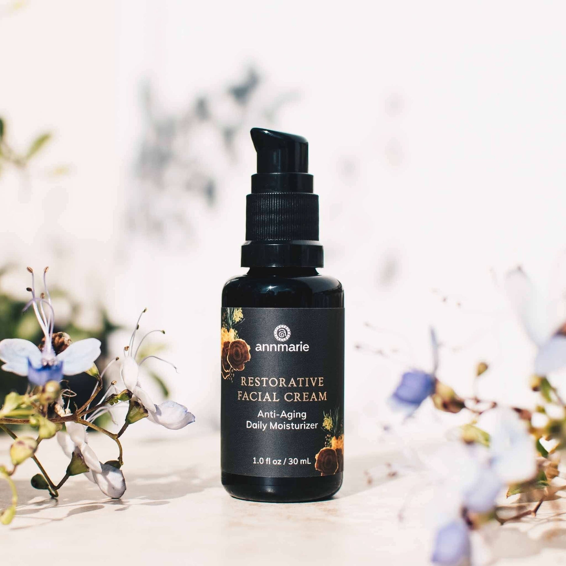 Restorative Facial Cream anti-aging daily moisturizer bottle styled with soft flowers on a light background