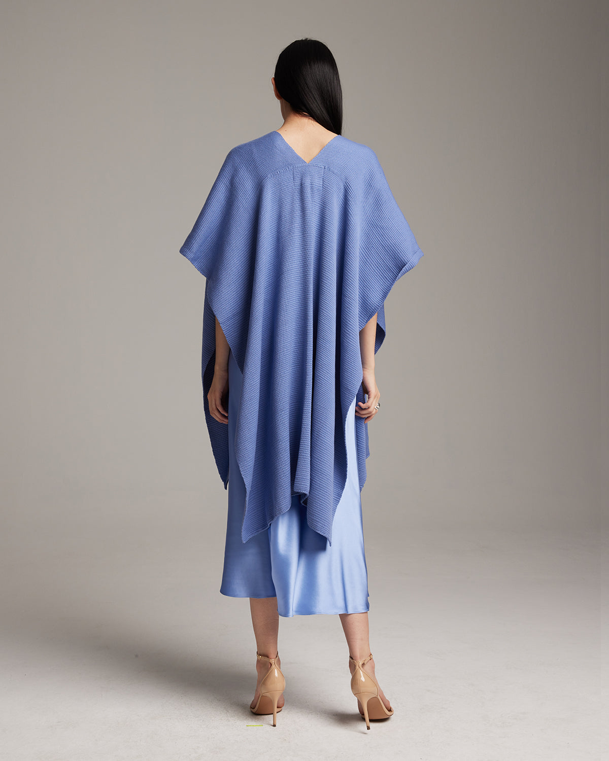 Model wearing a cornflower blue solid cotton duster from the back, paired with a slipdress.