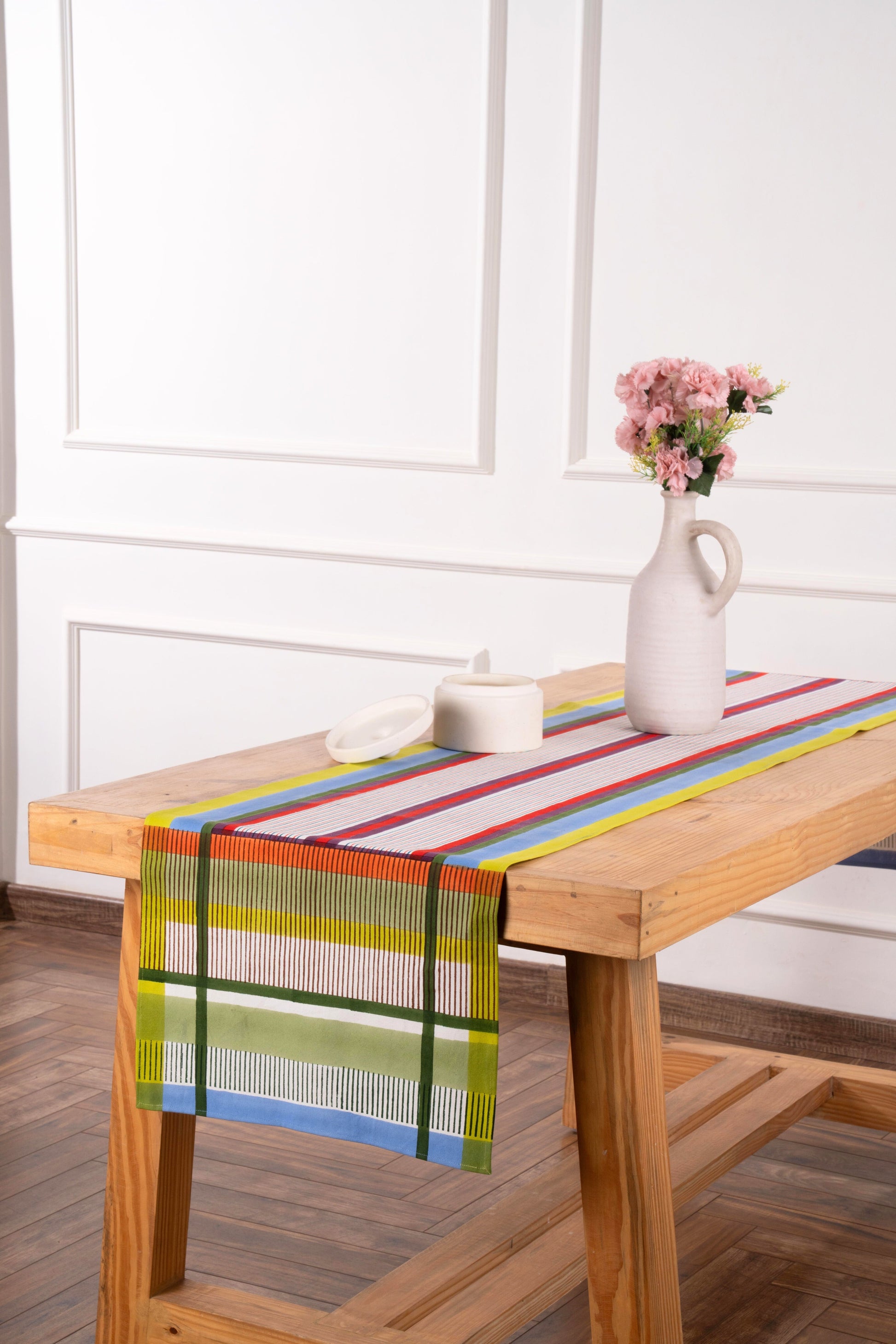 Modernist striped tablerunner on wooden table with white vase and pink flowers
