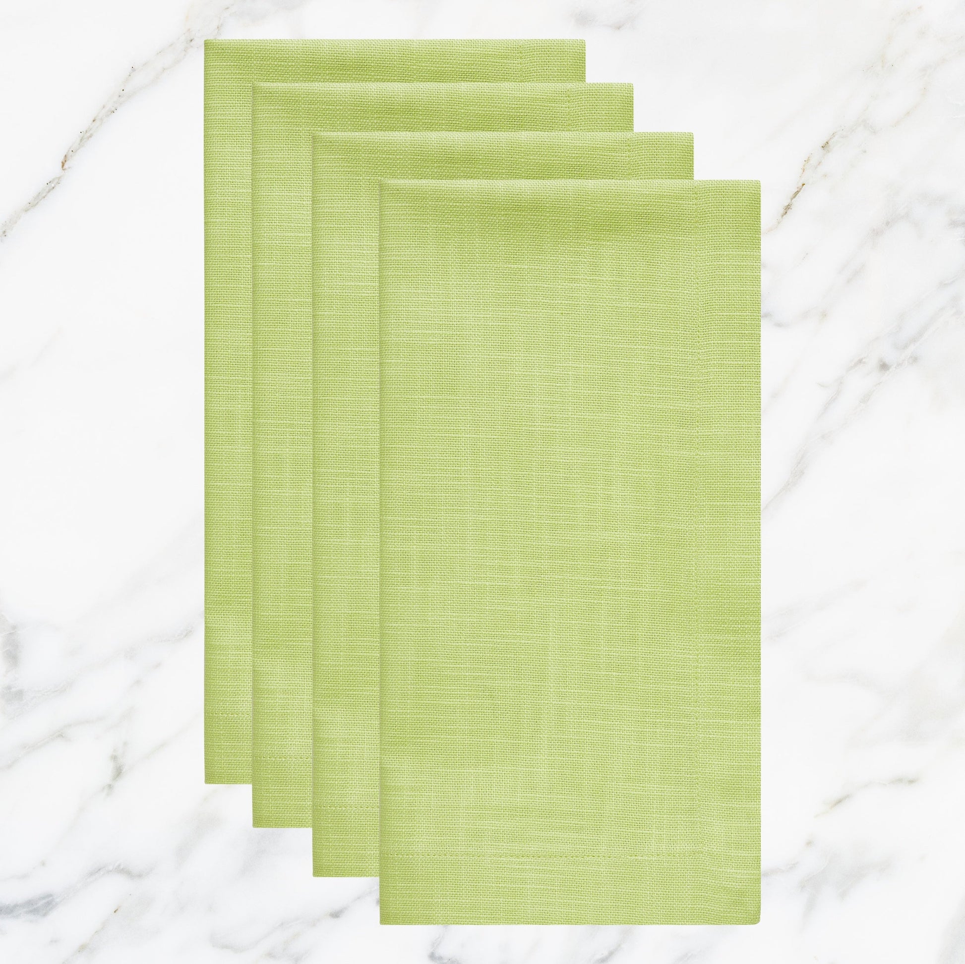 NP-4804-2020_1|Four folded lime green cloth dinner napkins on marble background. Vibrant reusable fabric napkins for spring, summer events.