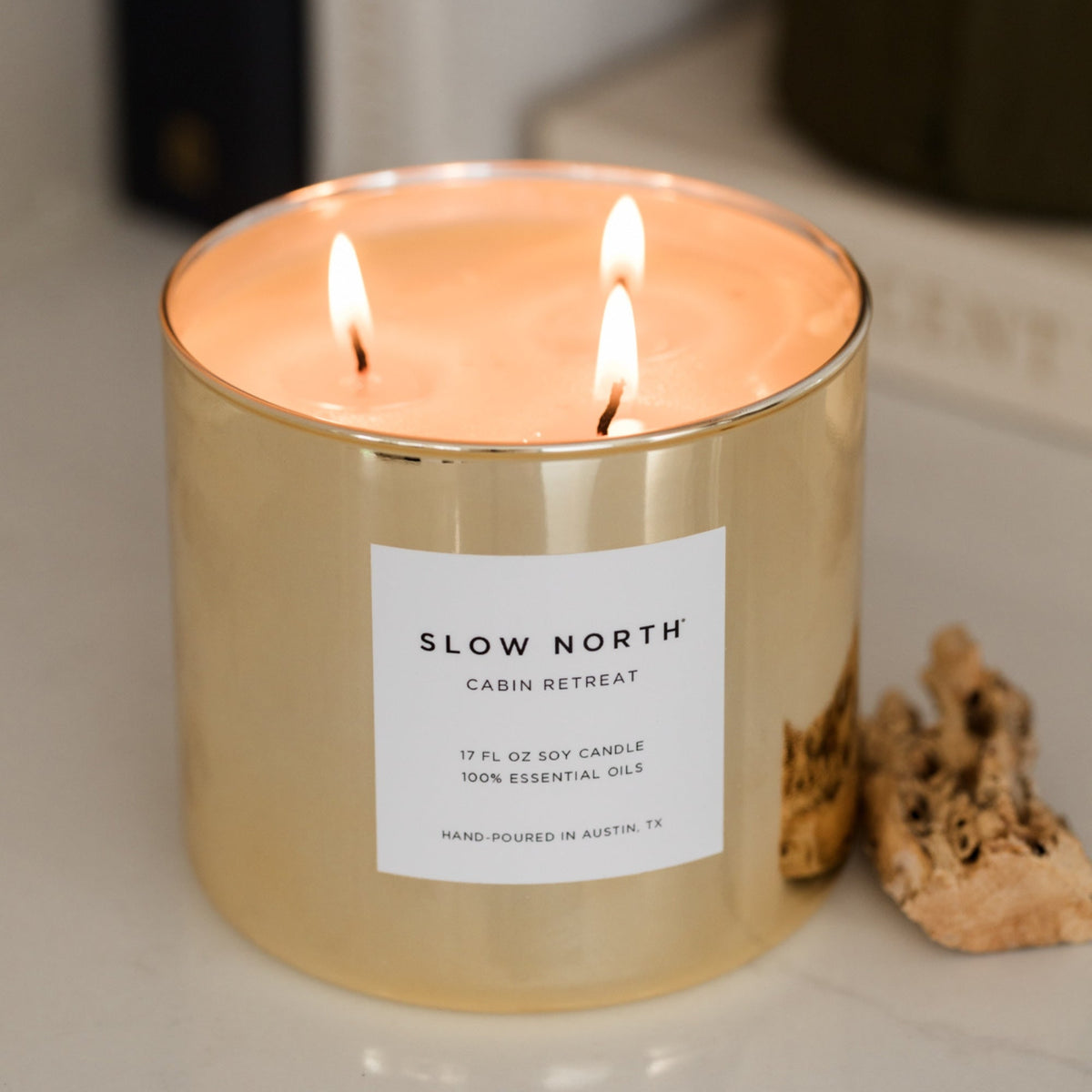 Gold candle with a label reading 'Slow North Cabin Retreat' on a neutral background.