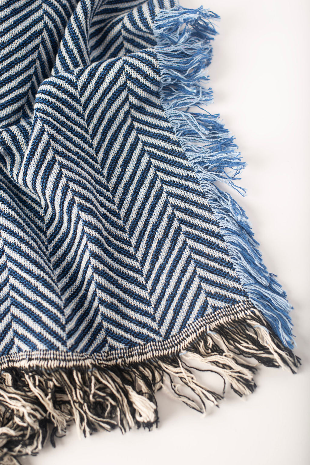 Close-up of Henry Chambray blue and cream herringbone woven cotton throw with blue fringe