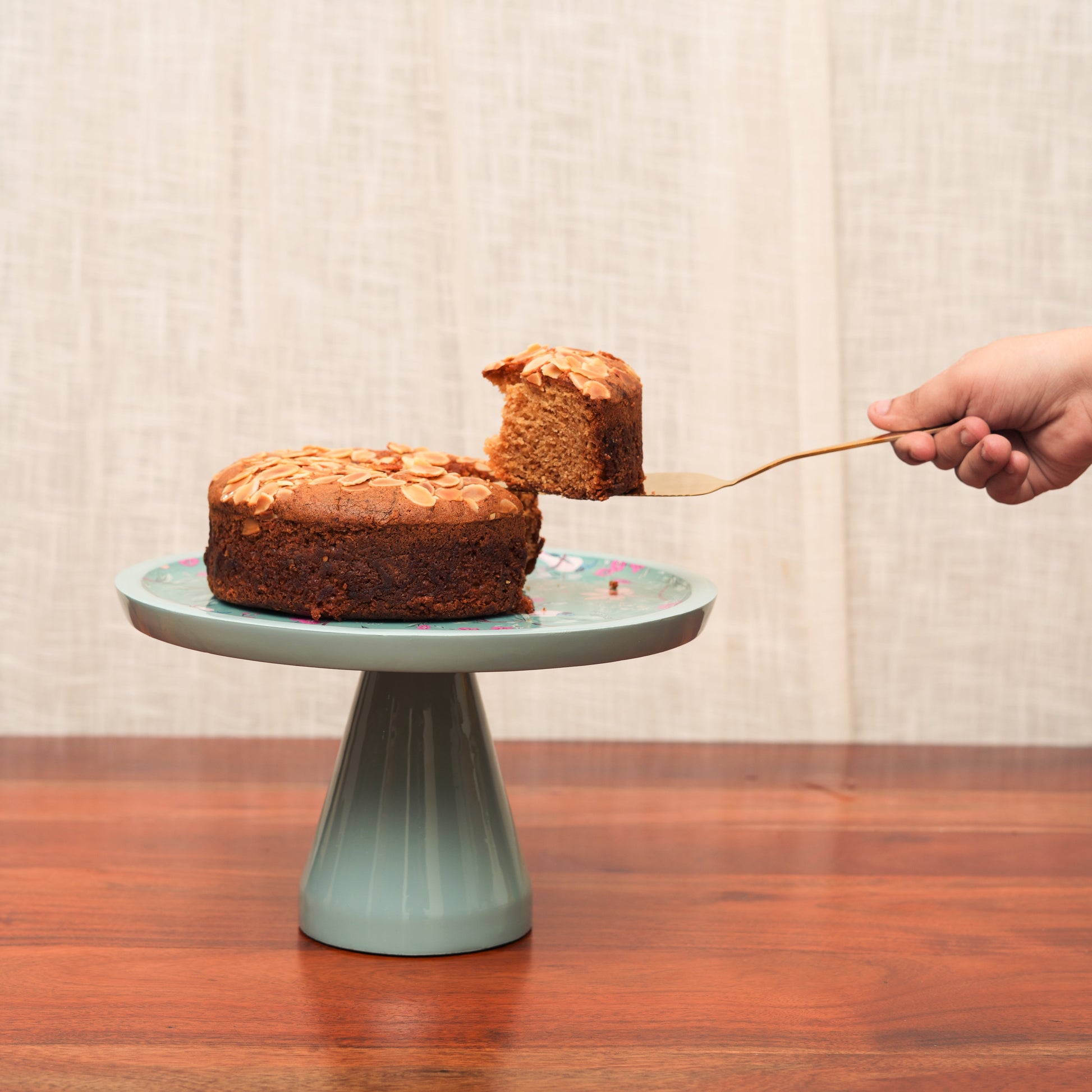 Handcrafted aqua cake stand styled with a chocolate ganache cake and a serving knife.