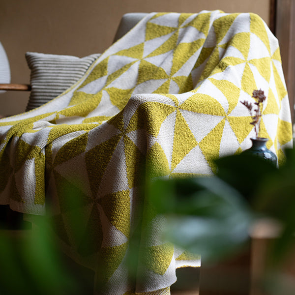 Bush green and white geometric patterned cotton throw draped over a chair in a home setting.