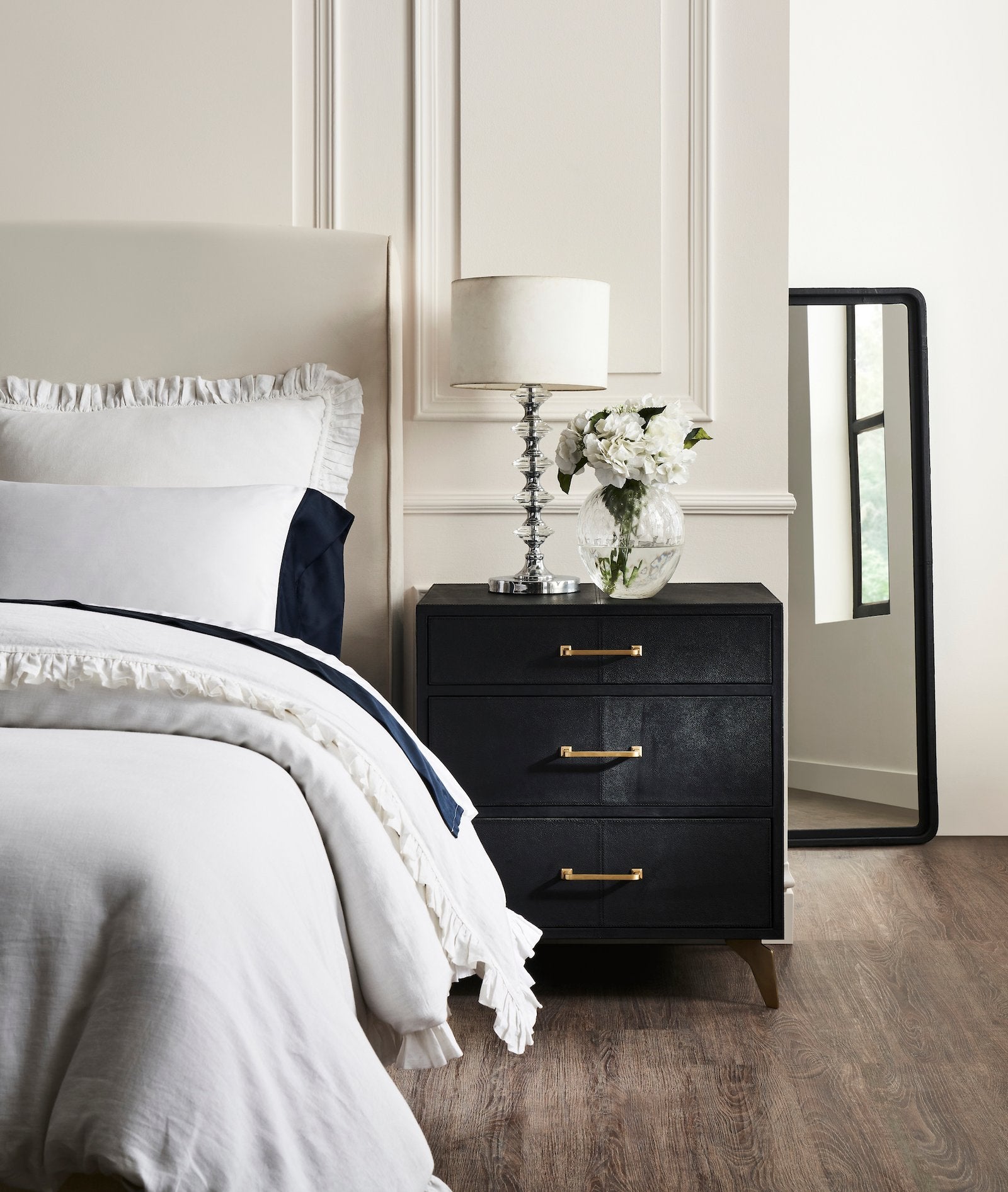 FN-5200-262028_1|Luxurious black leather furniture dresser with three drawers, gold handles, and brass legs, complementing a chic bedroom setting.