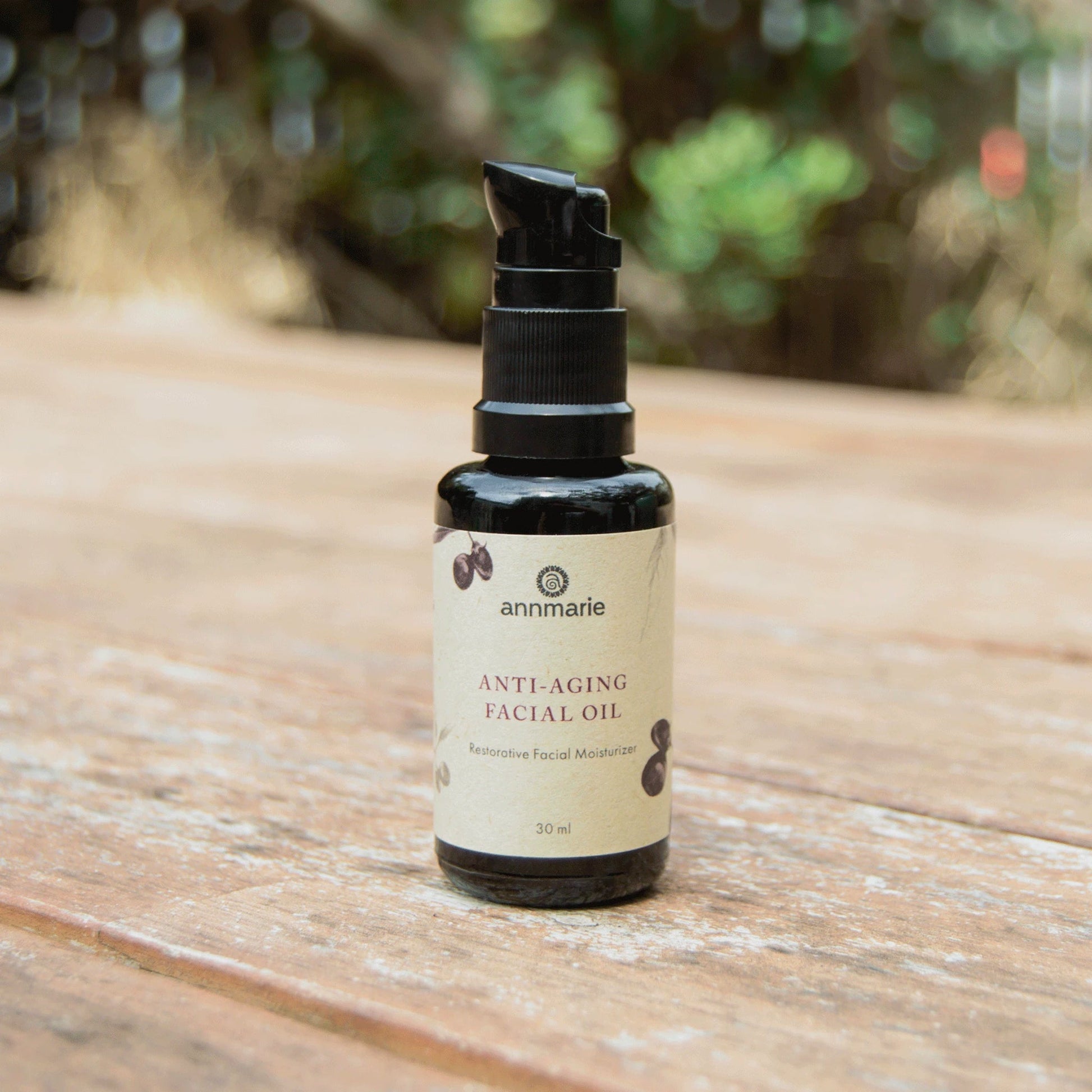 Anti-Aging Facial Oil restorative facial moisturizer bottle on wooden surface.