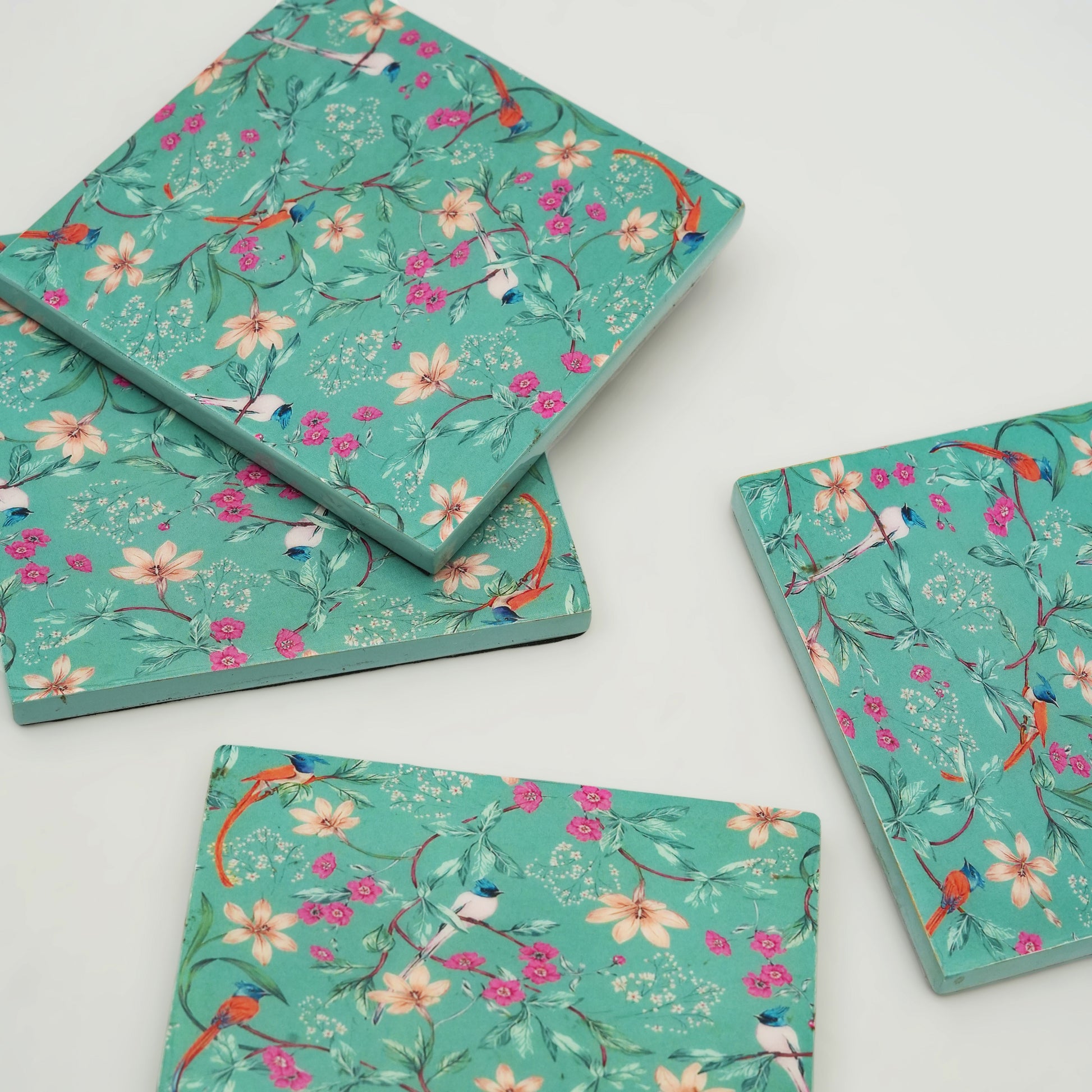 Floral and bird patterned notebooks on a white background