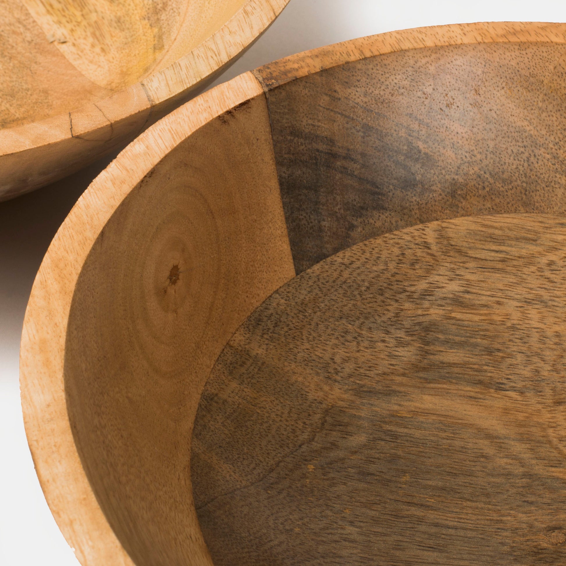Two round wooden serving bowls nested together to demonstrate compact, stackable kitchen storage.
