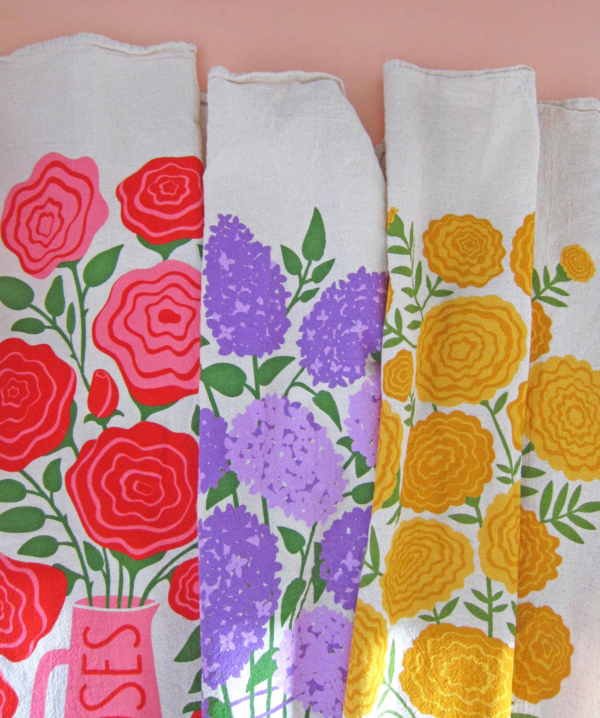 Rose, lilac, and marigold floral-themed kitchen tea towels laid side by side.