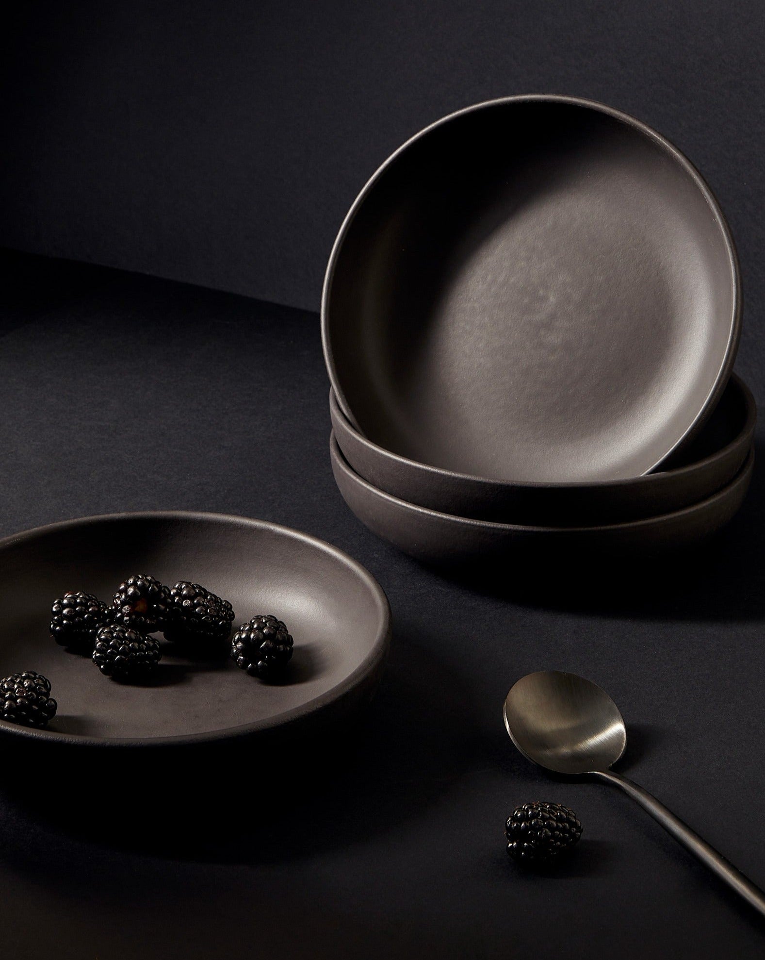 A set of white stoneware pasta plates with a matte finish, including a serving suggestion with pasta on one of the plates, displayed on a neutral background.