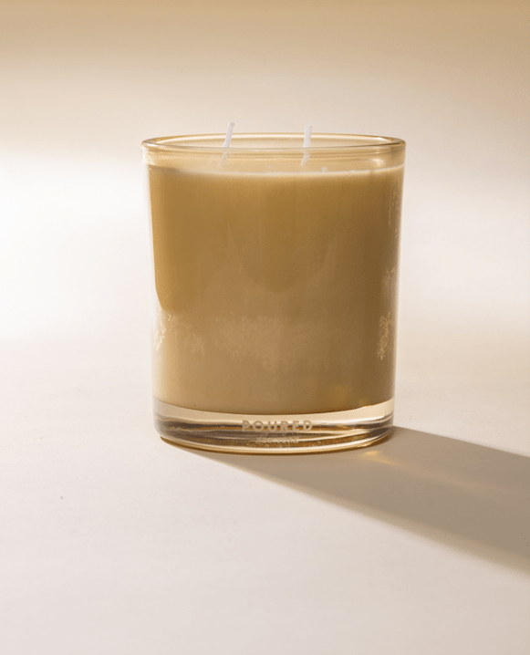 Poured New York 'Mellow Pomelo' Two Wick candle in a butter yellow glass on a neutral background.