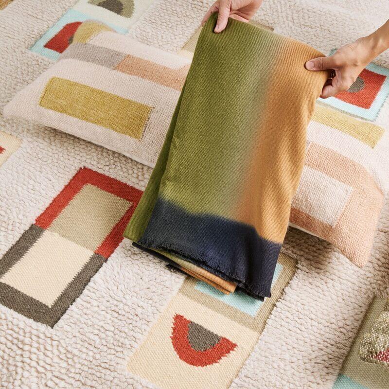 Shale Hand Woven Pastel Color Large Geometric Lumbar Pillow on a textured surface with colorful patterns.