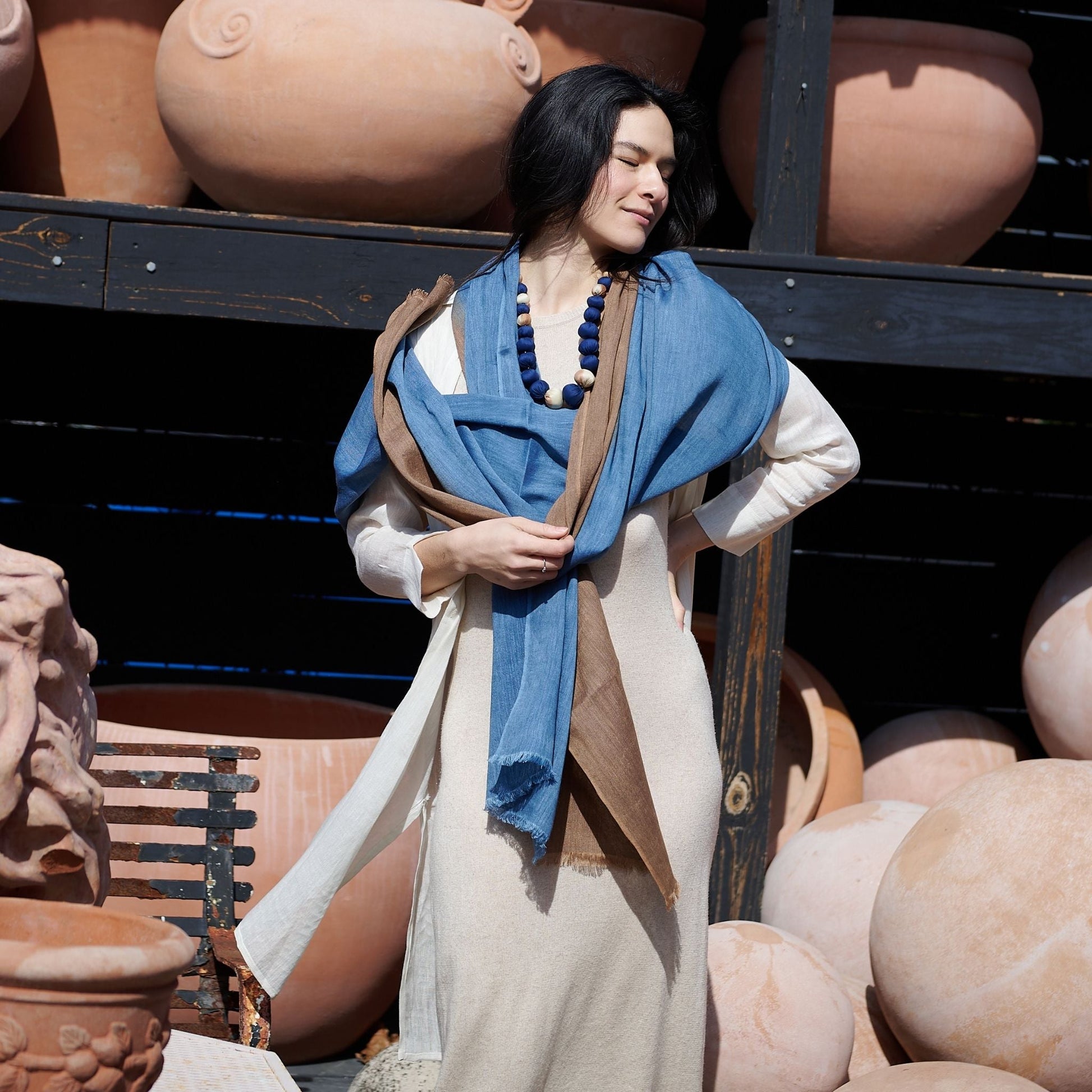 Woman standing with a draped Mahogany Sky Brown Indigo Linen Scarf scarf with silk beaded jewelry styled. 