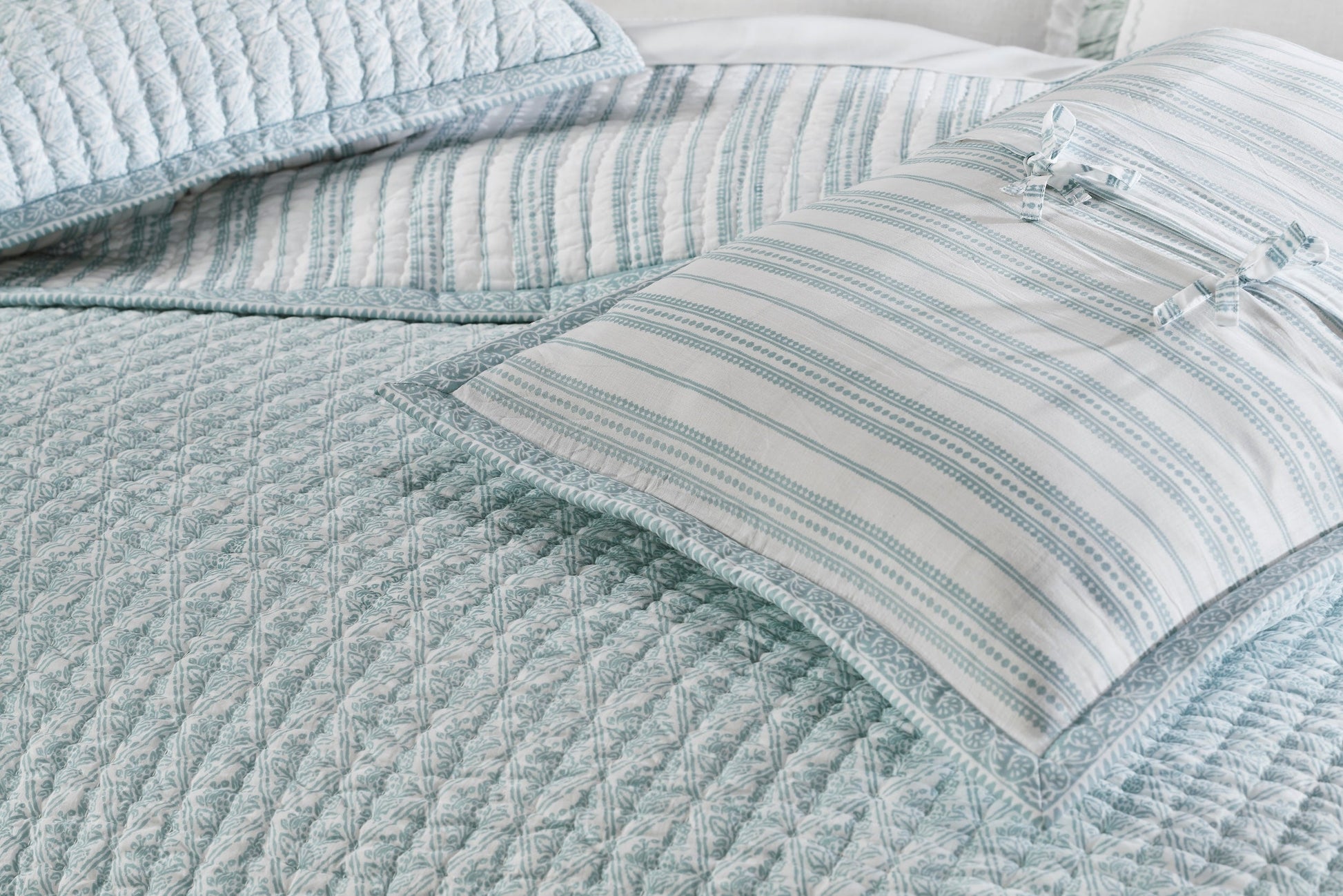 QT-347-11096_5|Stylish blue patterned quilt on a bed, paired with complementary striped pillows, offering soft texture and an elegant bedding design.